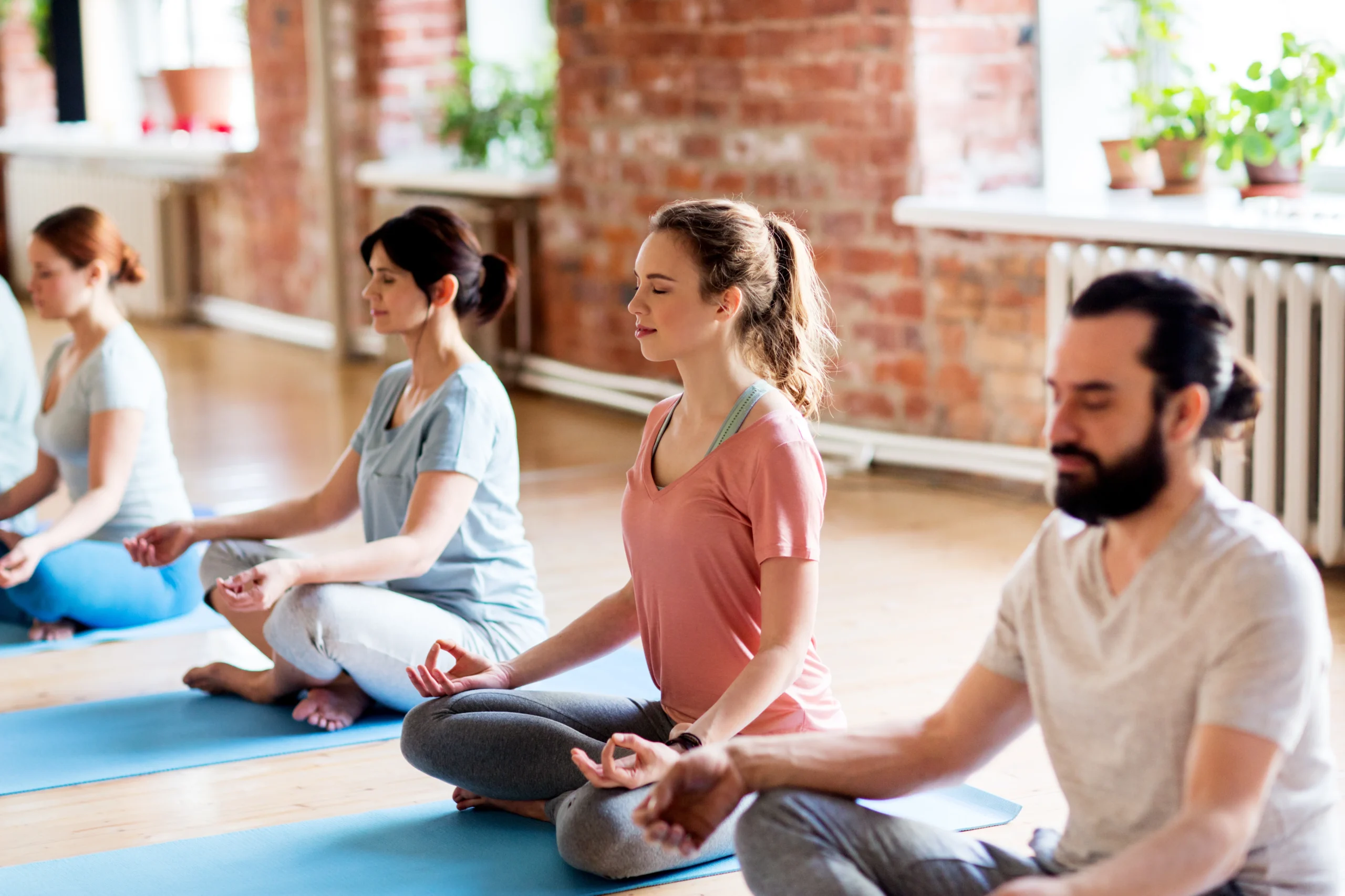 Group of adults practicing guided meditation together in a calm studio setting.