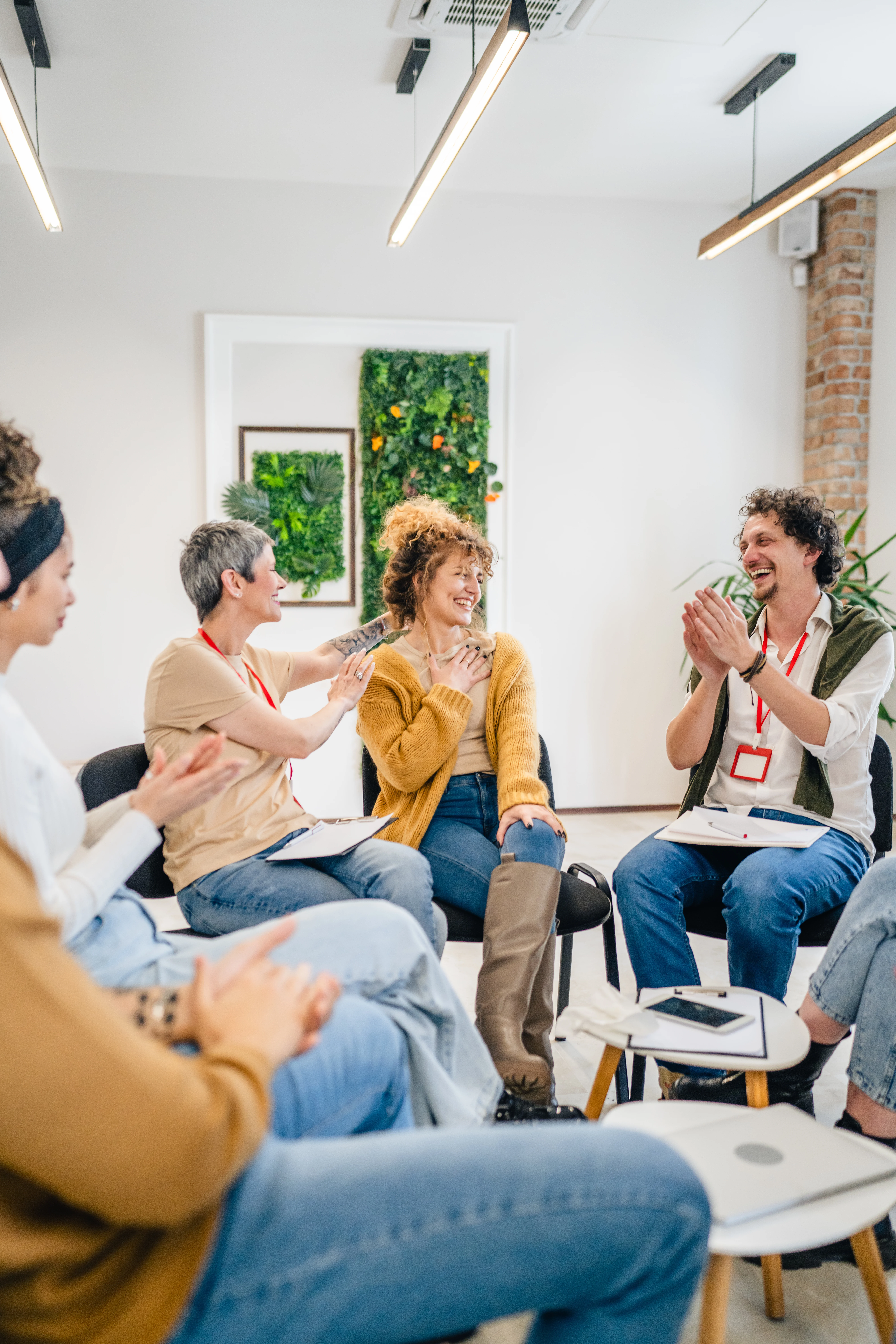 Group therapy participants applauding a woman during a mental health support session.