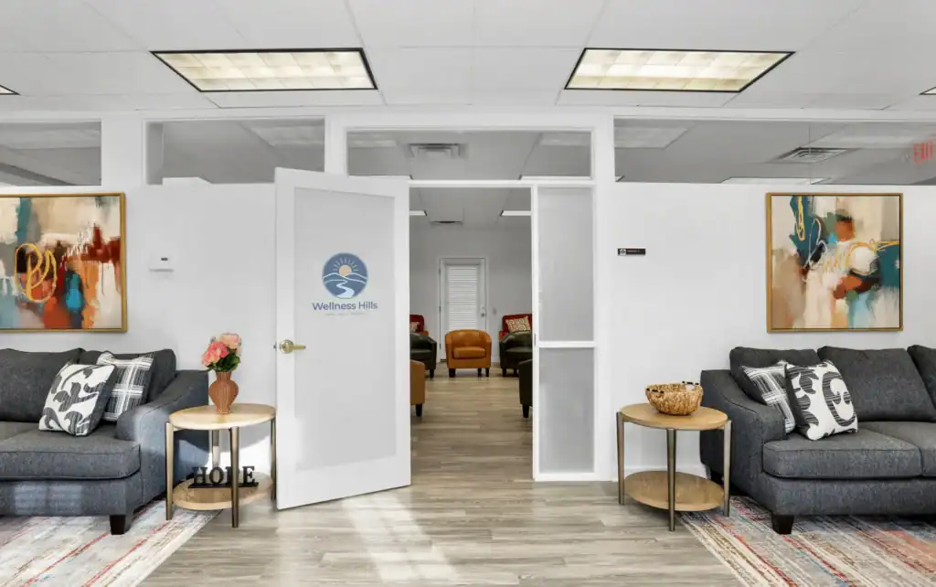 Entrance to the group therapy room at Wellness Hills Mental Health Treatment with couches, artwork, and open door leading to seating area.