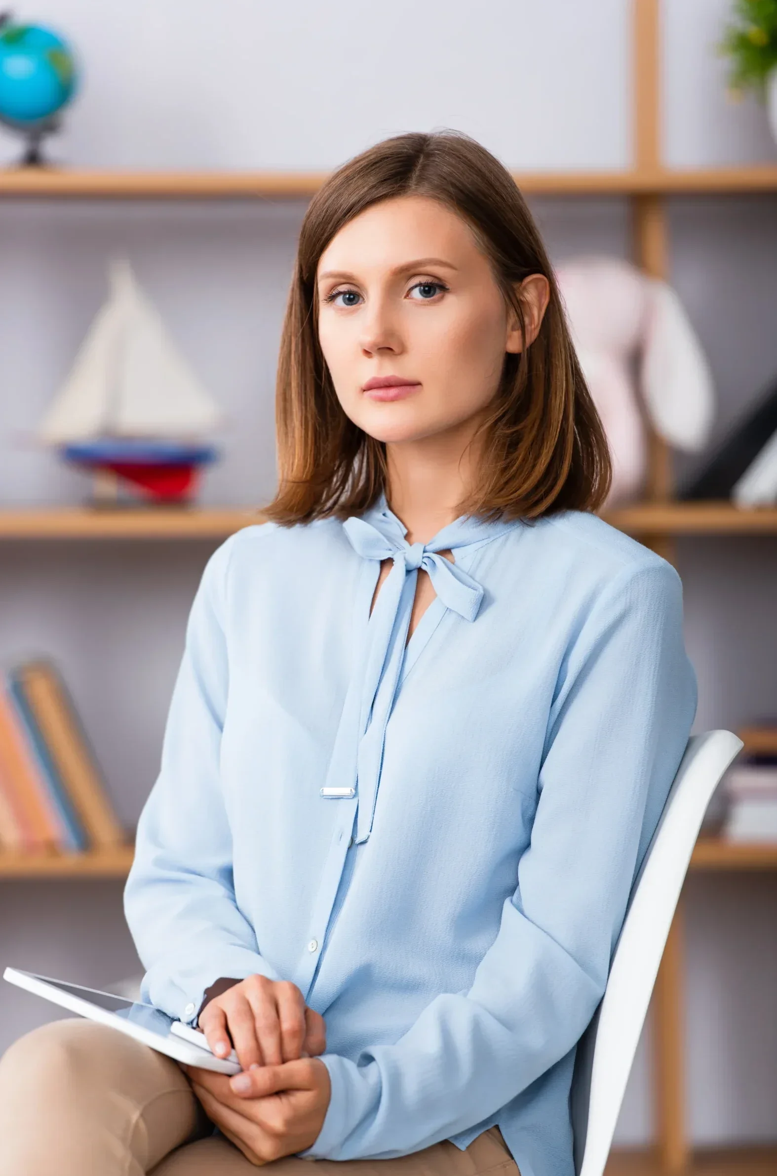 Female therapist sitting with a tablet in her lap during a mental health session.