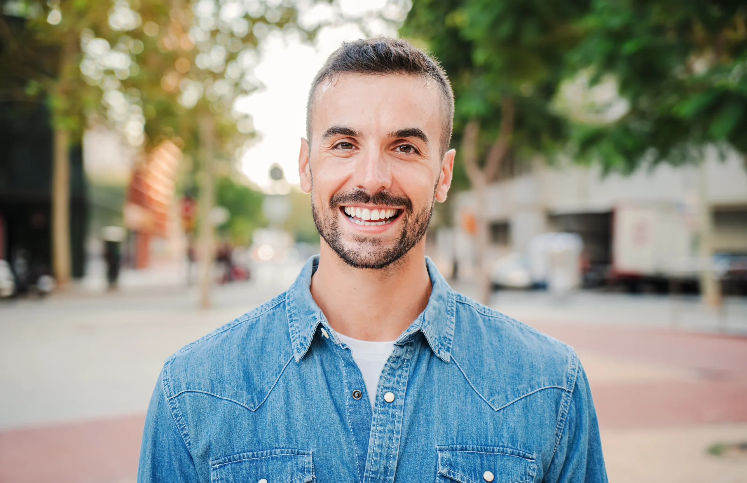 Smiling man standing outdoors on a city street, representing confidence and positive mental well-being.