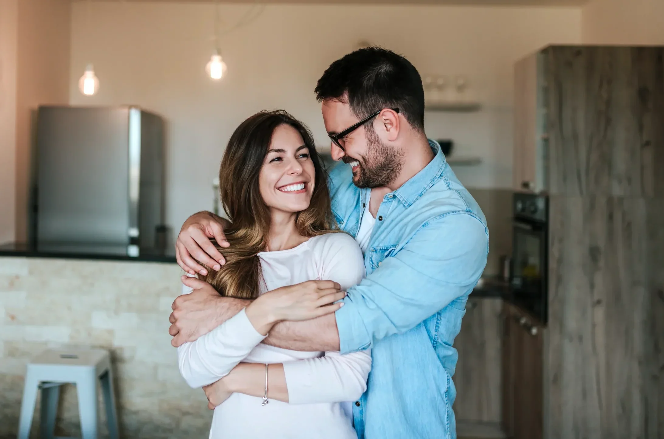 Smiling couple embracing in their home, representing emotional connection and mental wellness.