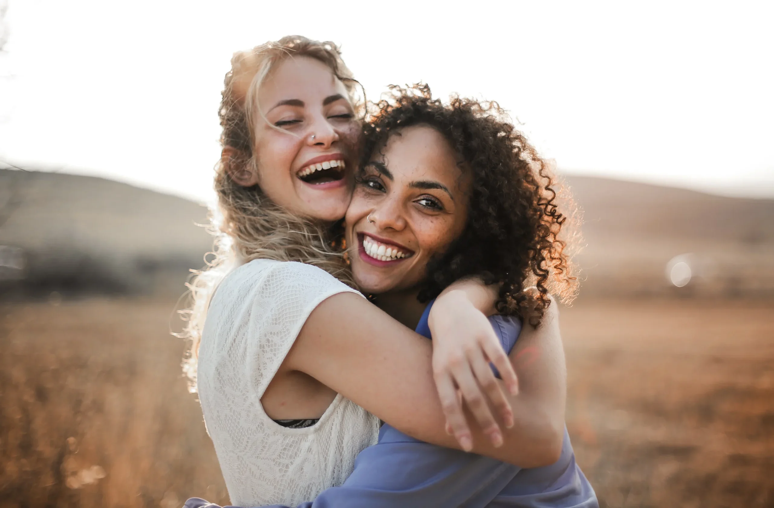 Two women embracing in nature.