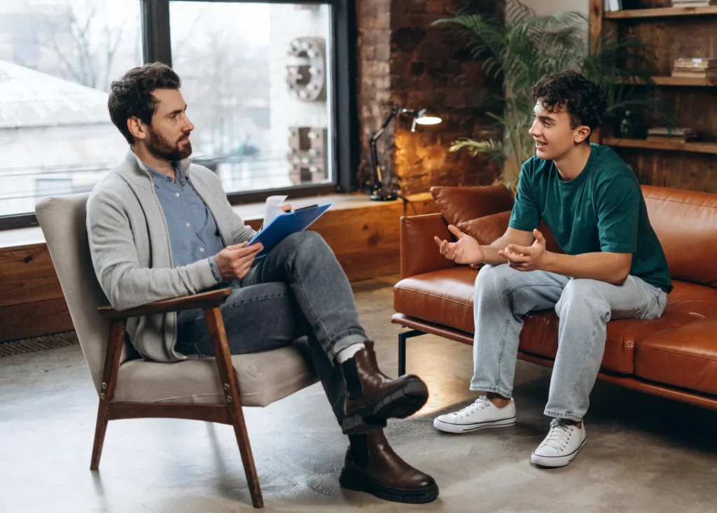 Young man meeting with a male mental health therapist during a counseling session.
