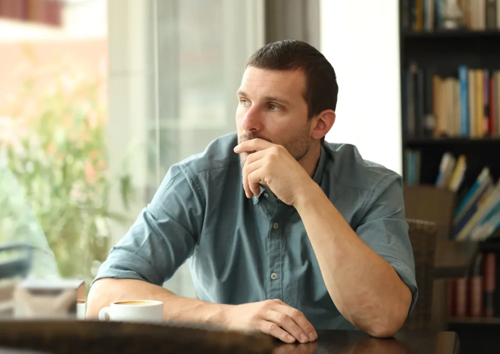 Man sitting at a cafe looking thoughtful, representing bipolar disorder and emotional reflection.