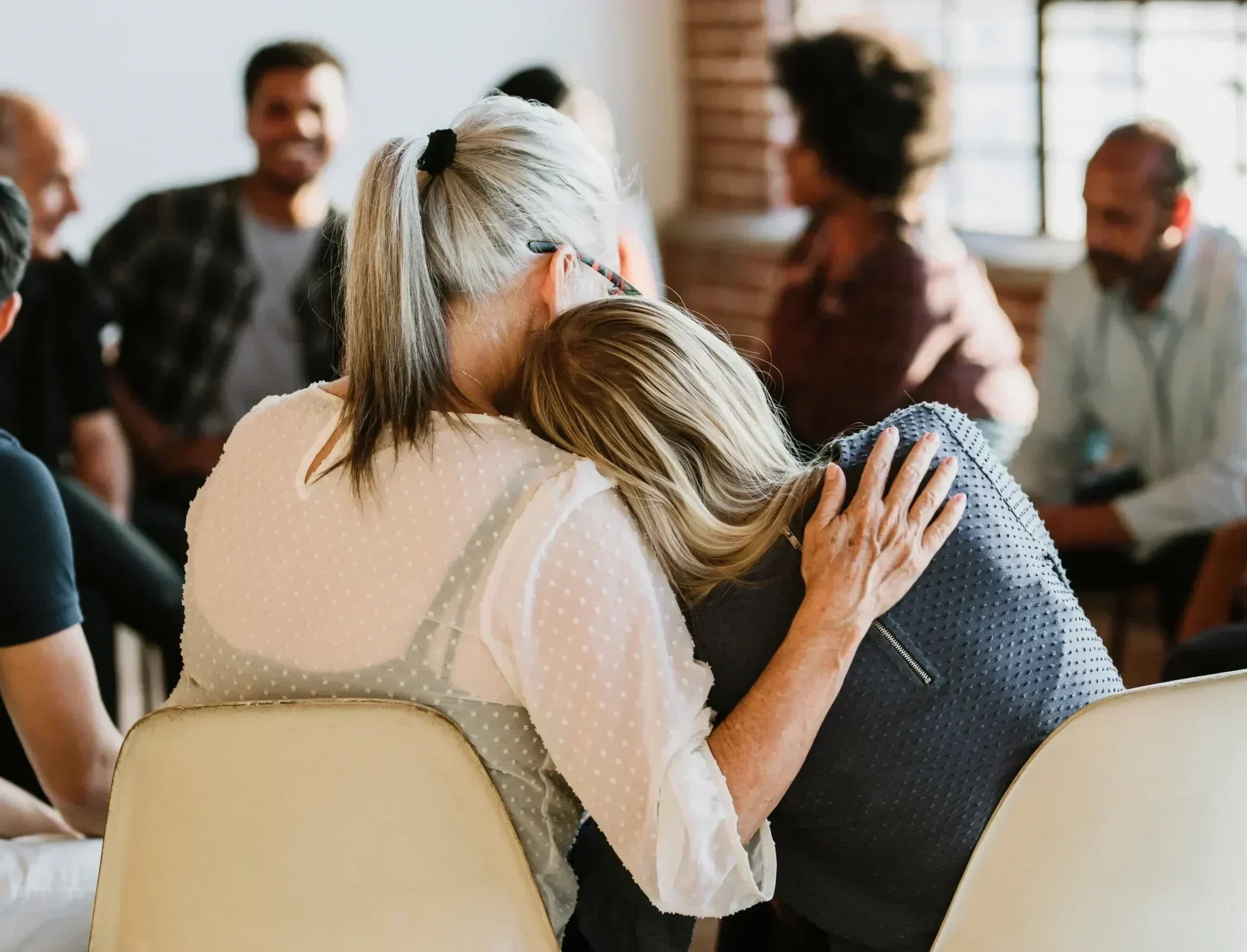 Woman comforting another person during a supportive mental health group session.