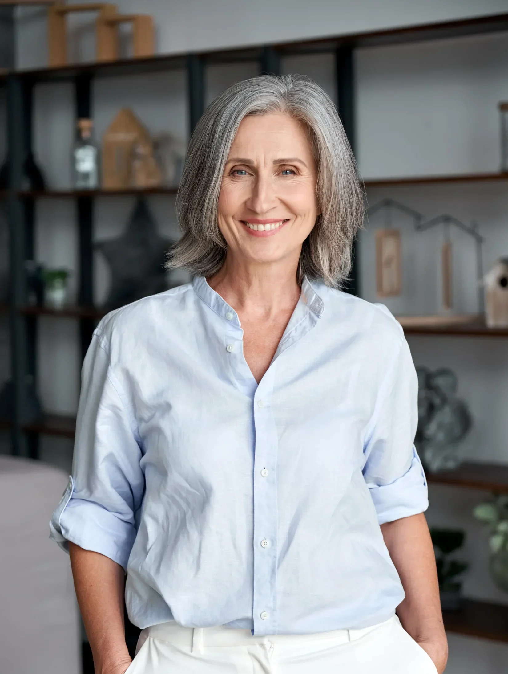 Smiling older woman standing confidently in a bright, modern living space.