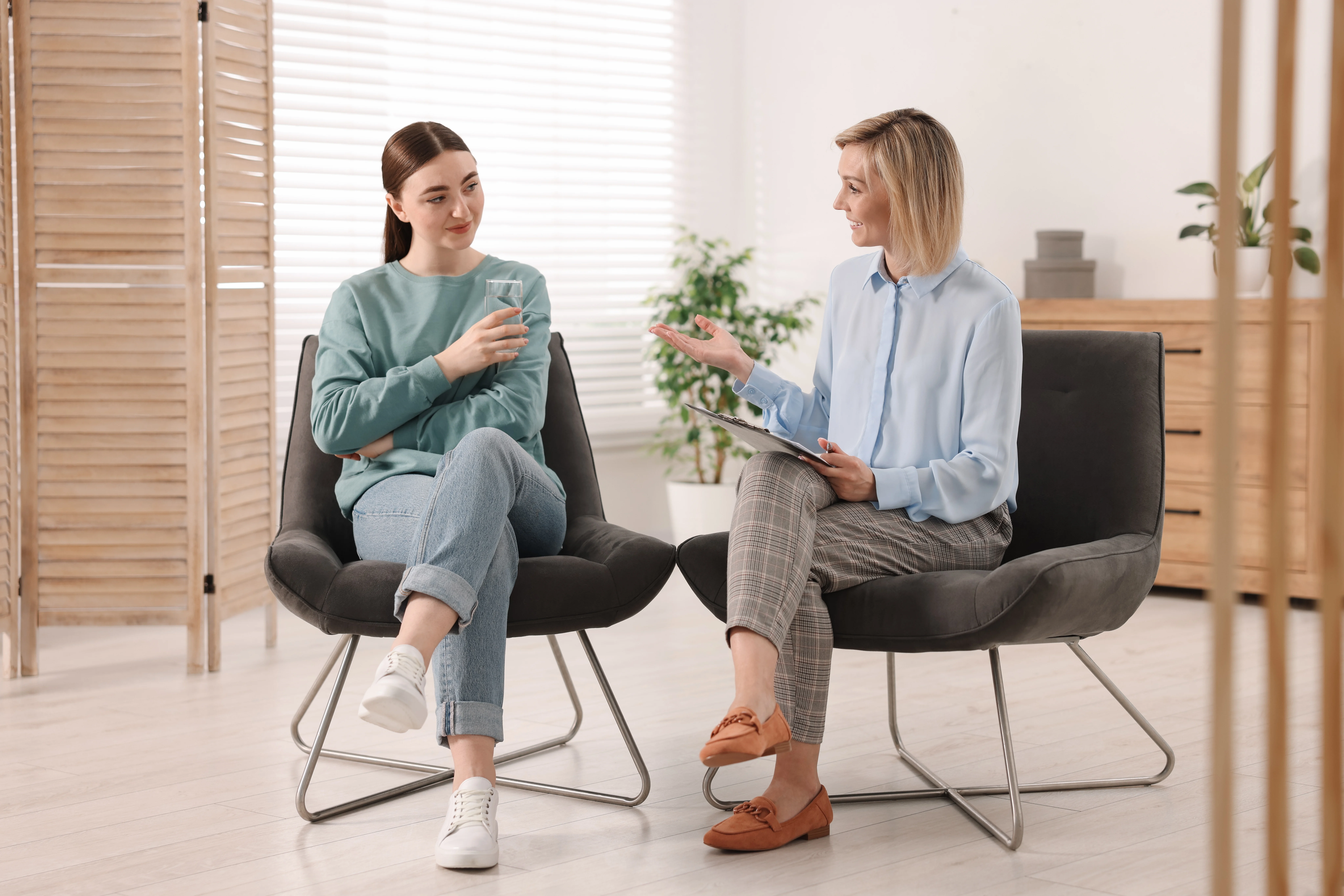 Female therapist speaking with young adult during one-on-one mental health counseling session.