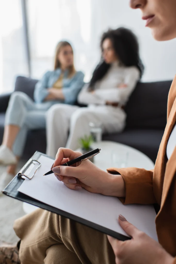 Therapist taking notes during a mental health session with two women