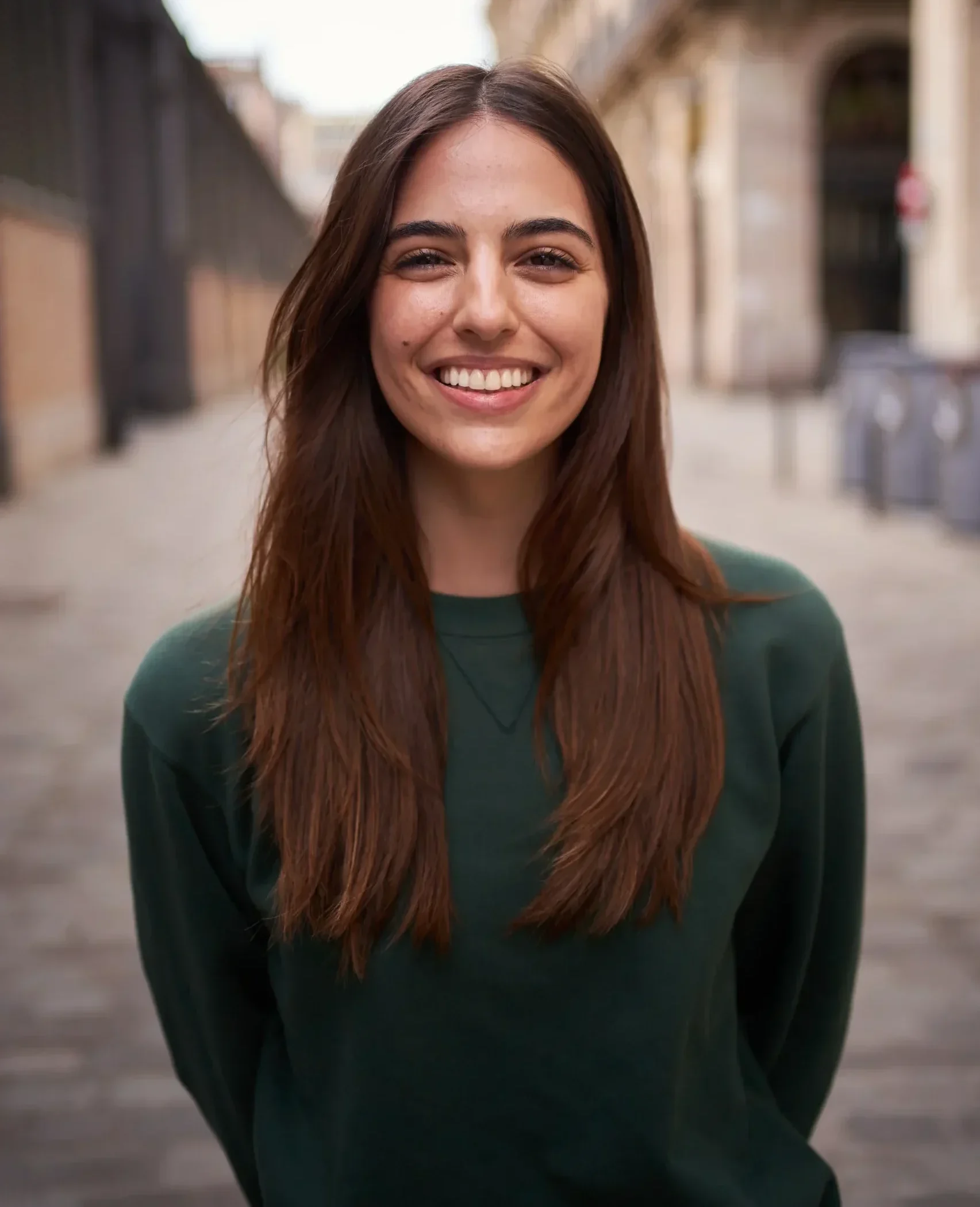 Woman standing in outdoor setting smiling.