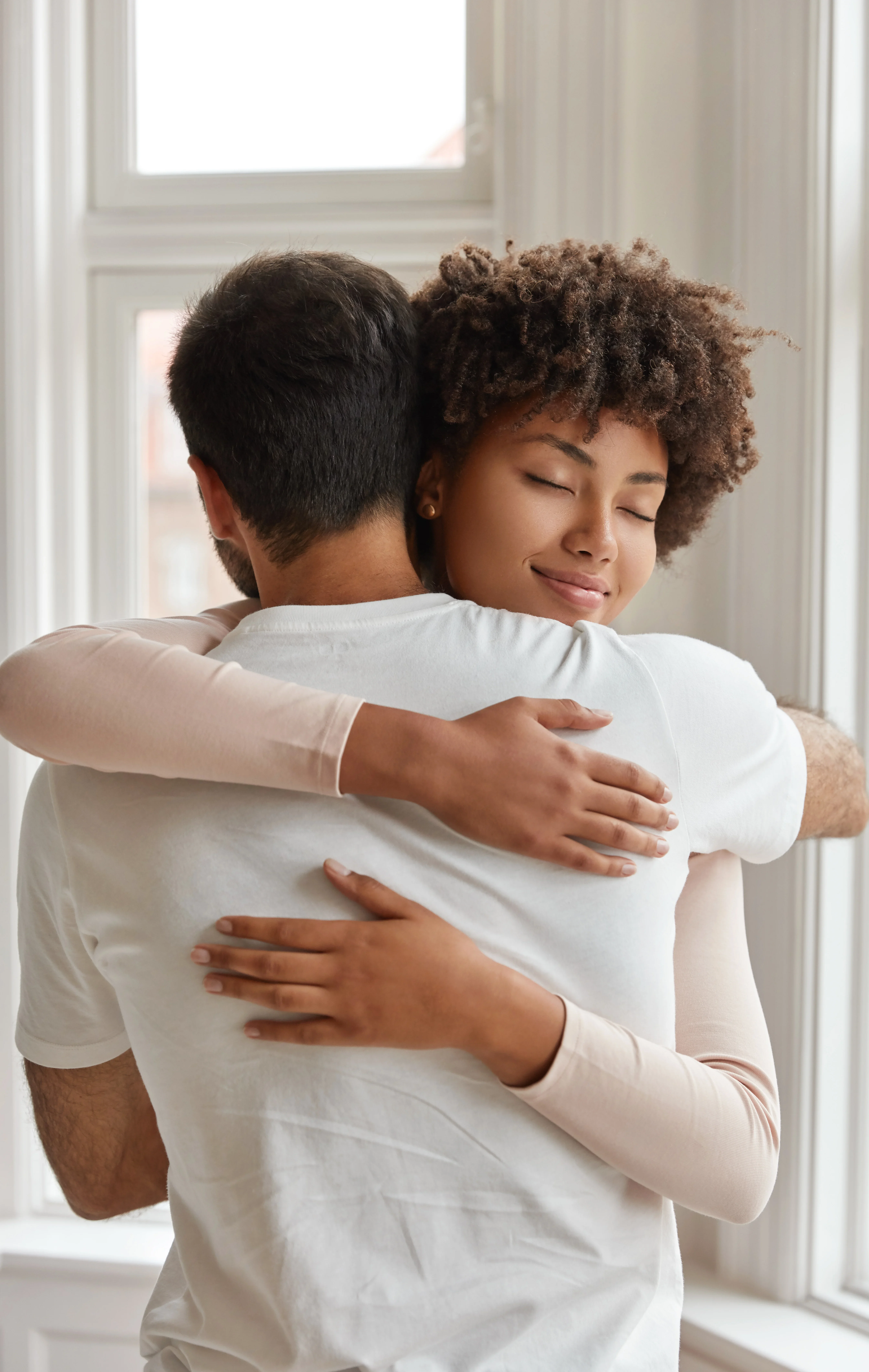 Woman hugging a man with a calm, supportive expression during emotional moment.