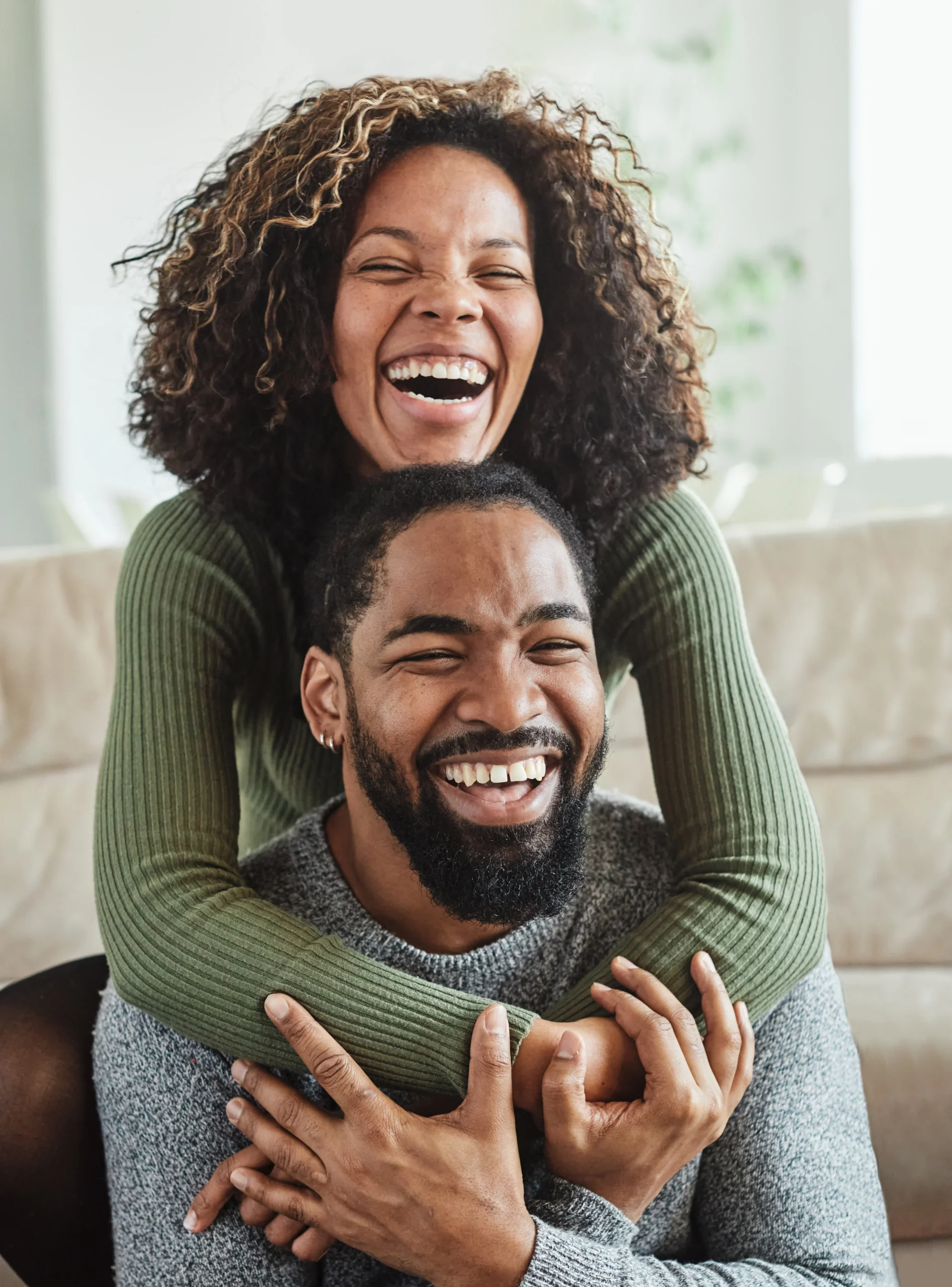 Happy couple embracing and laughing together in a supportive, healthy relationship.