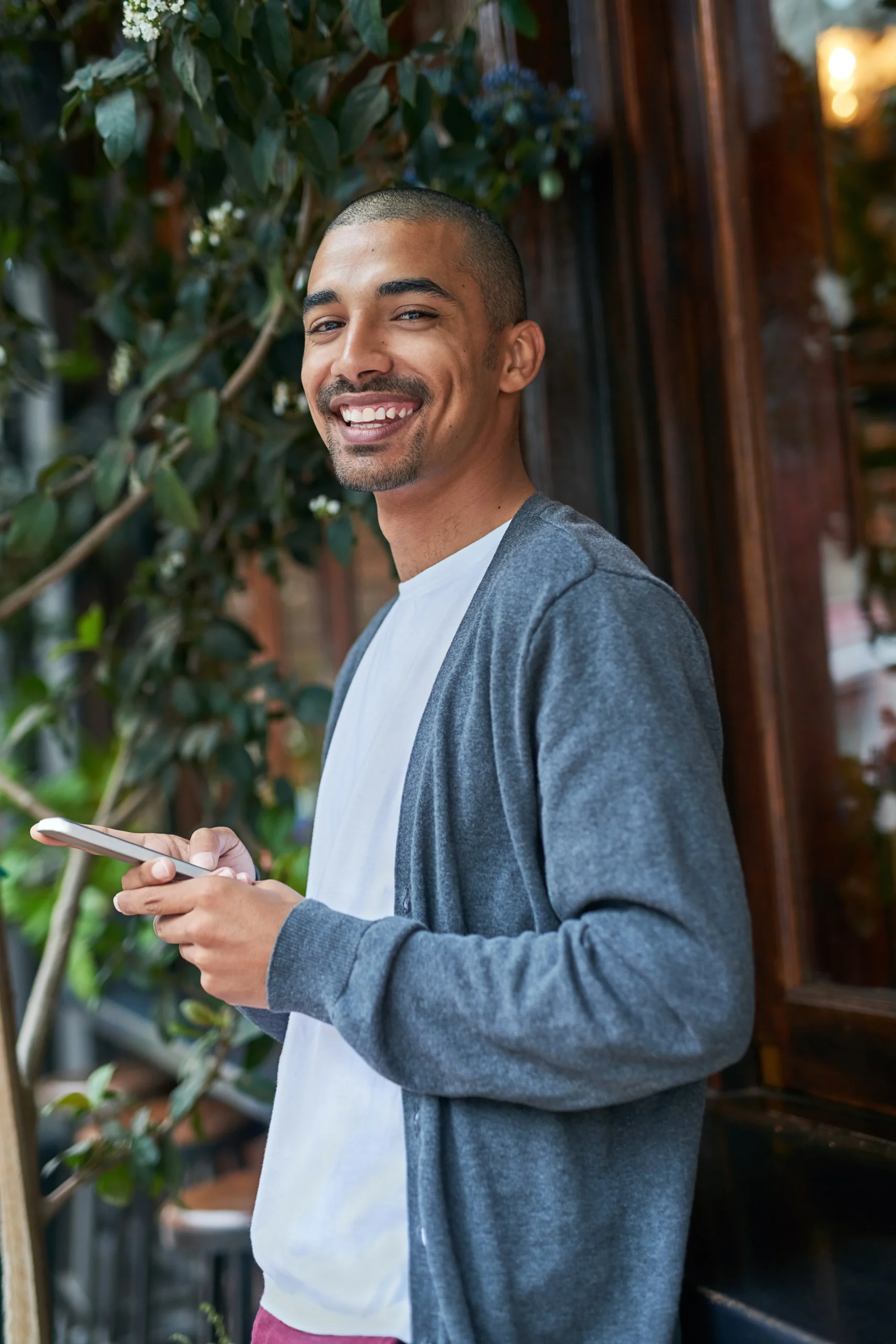 Young man smiling while using his phone outdoors.