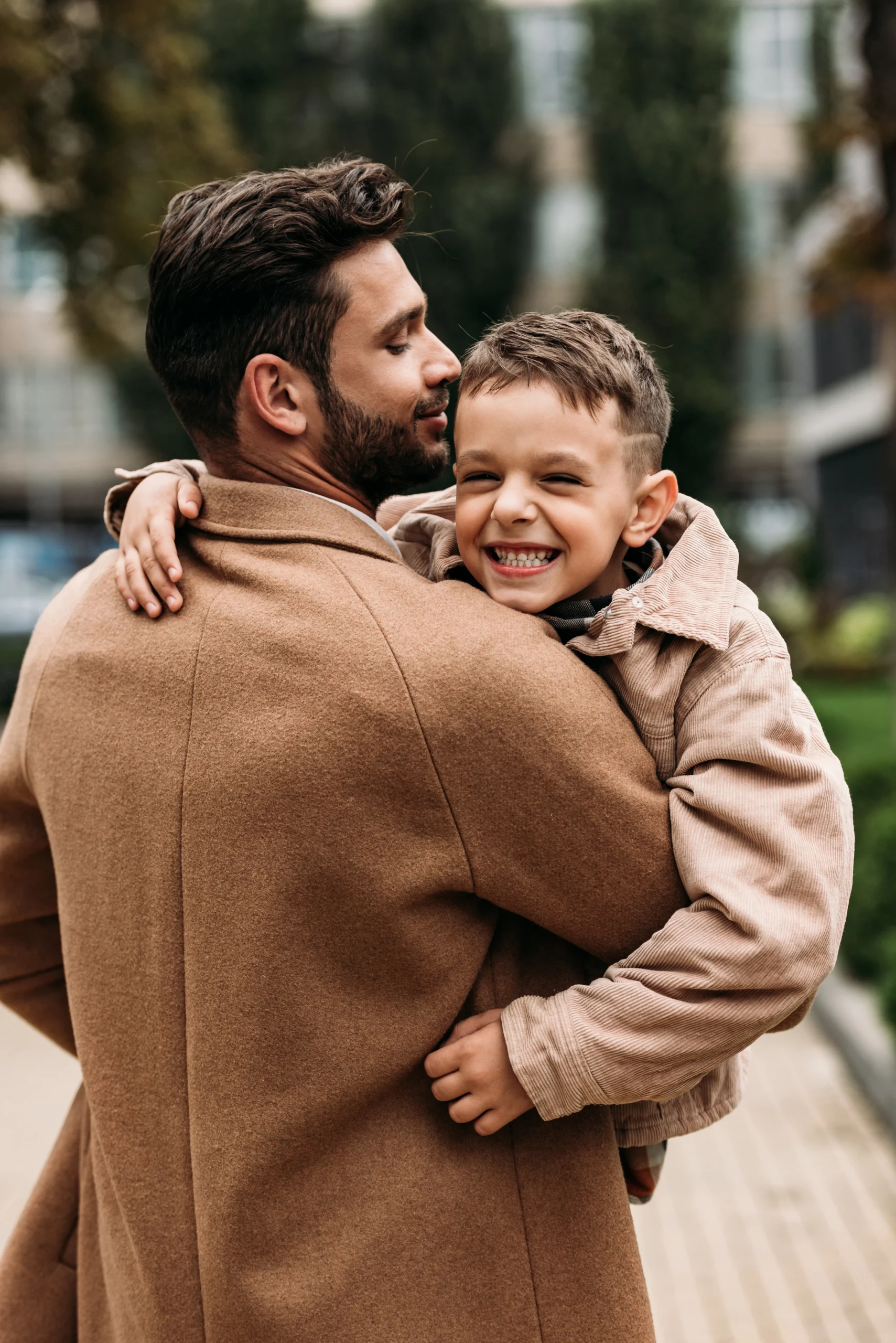 Father holding his smiling young son outdoors, representing family support and emotional connection