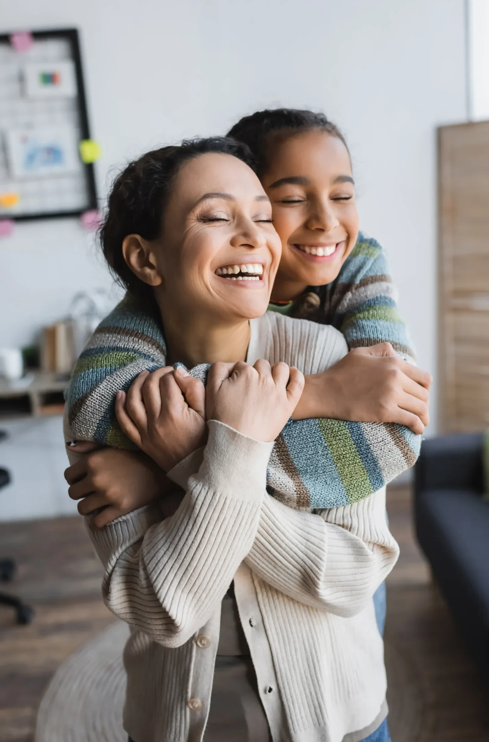 Smiling mother and child sharing a warm hug in a bright home office setting