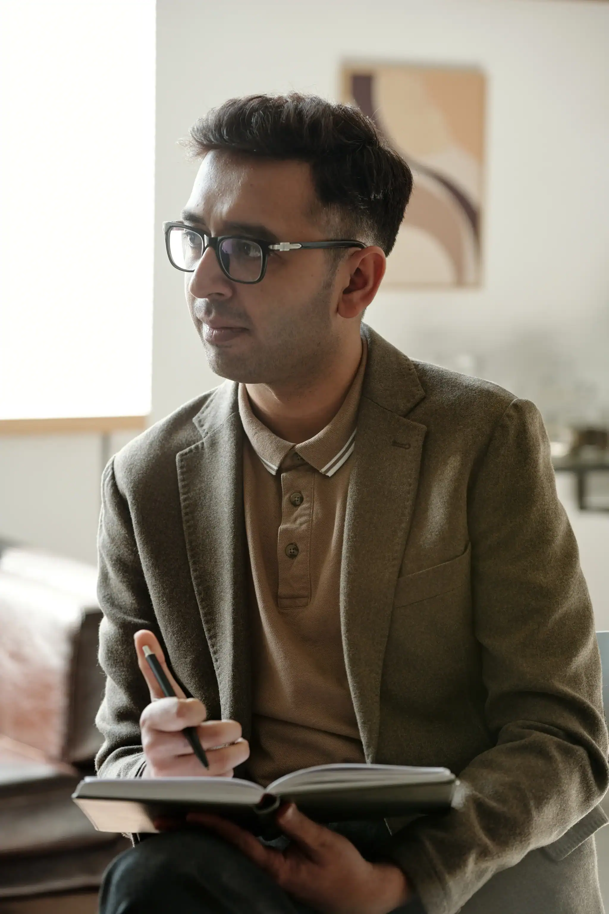 Mental health professional taking notes during a counseling session in a private office setting
