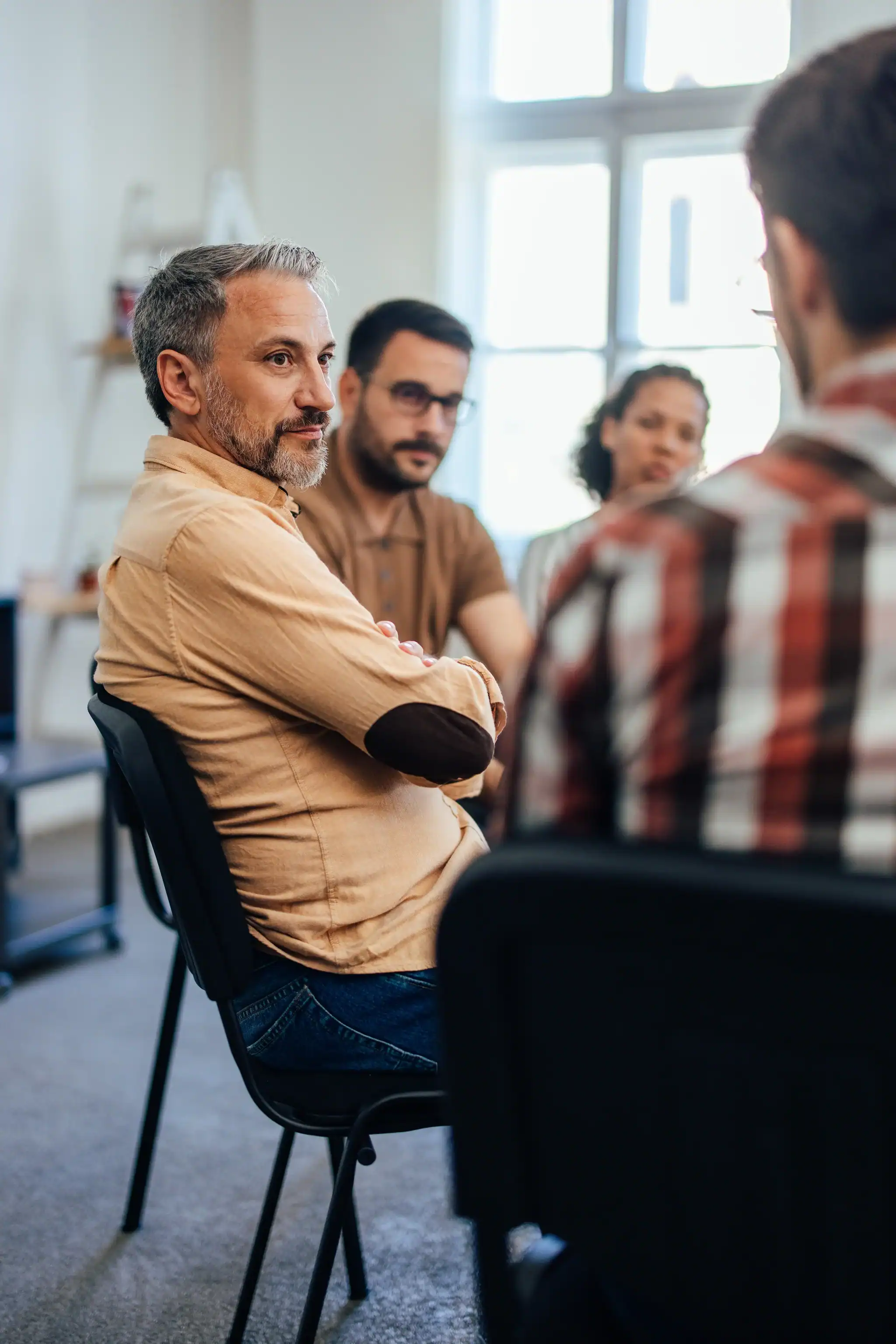 Adults participating in a group therapy session, listening and sharing in a structured, supportive environment