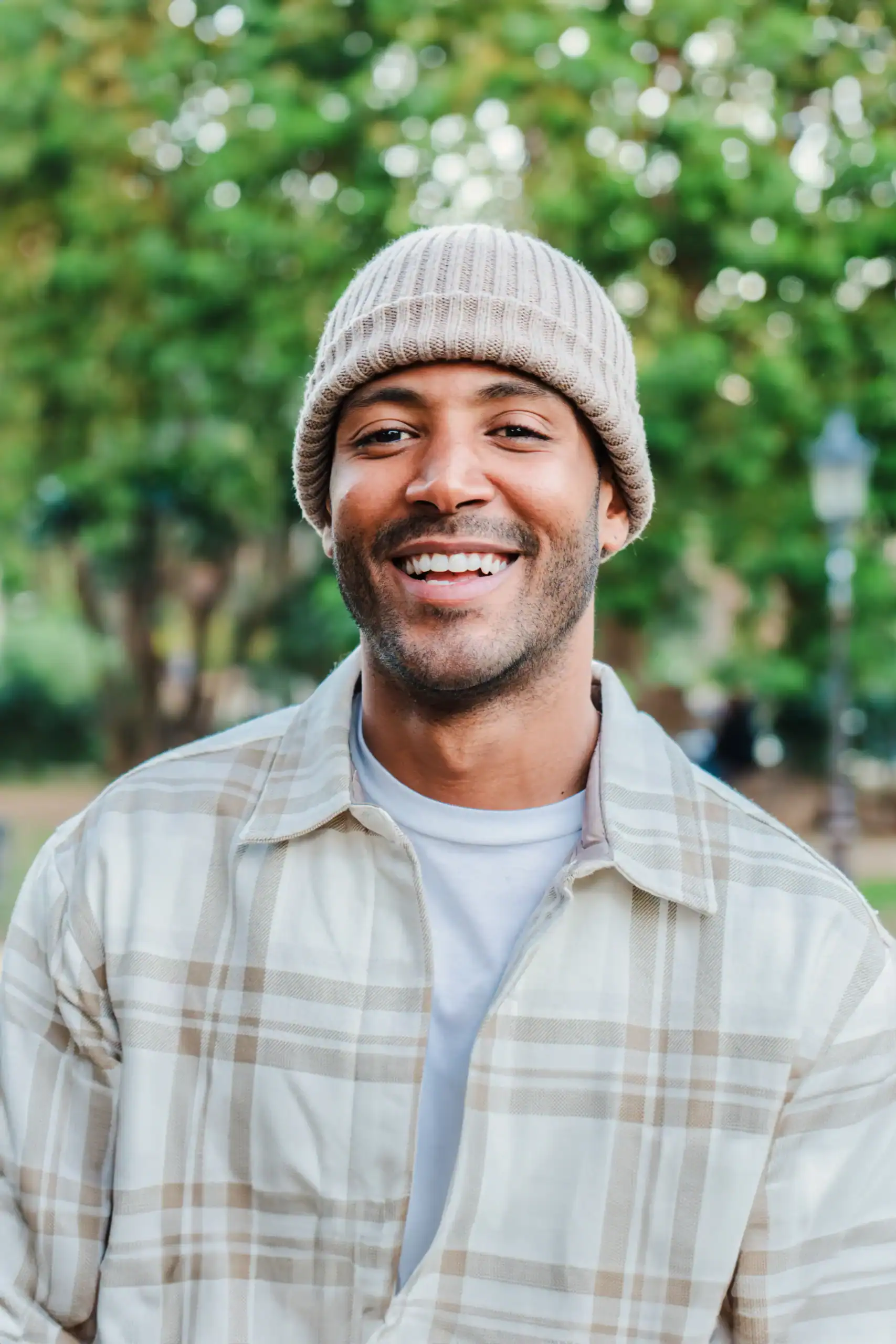 Smiling man outdoors in a park wearing a knit beanie
