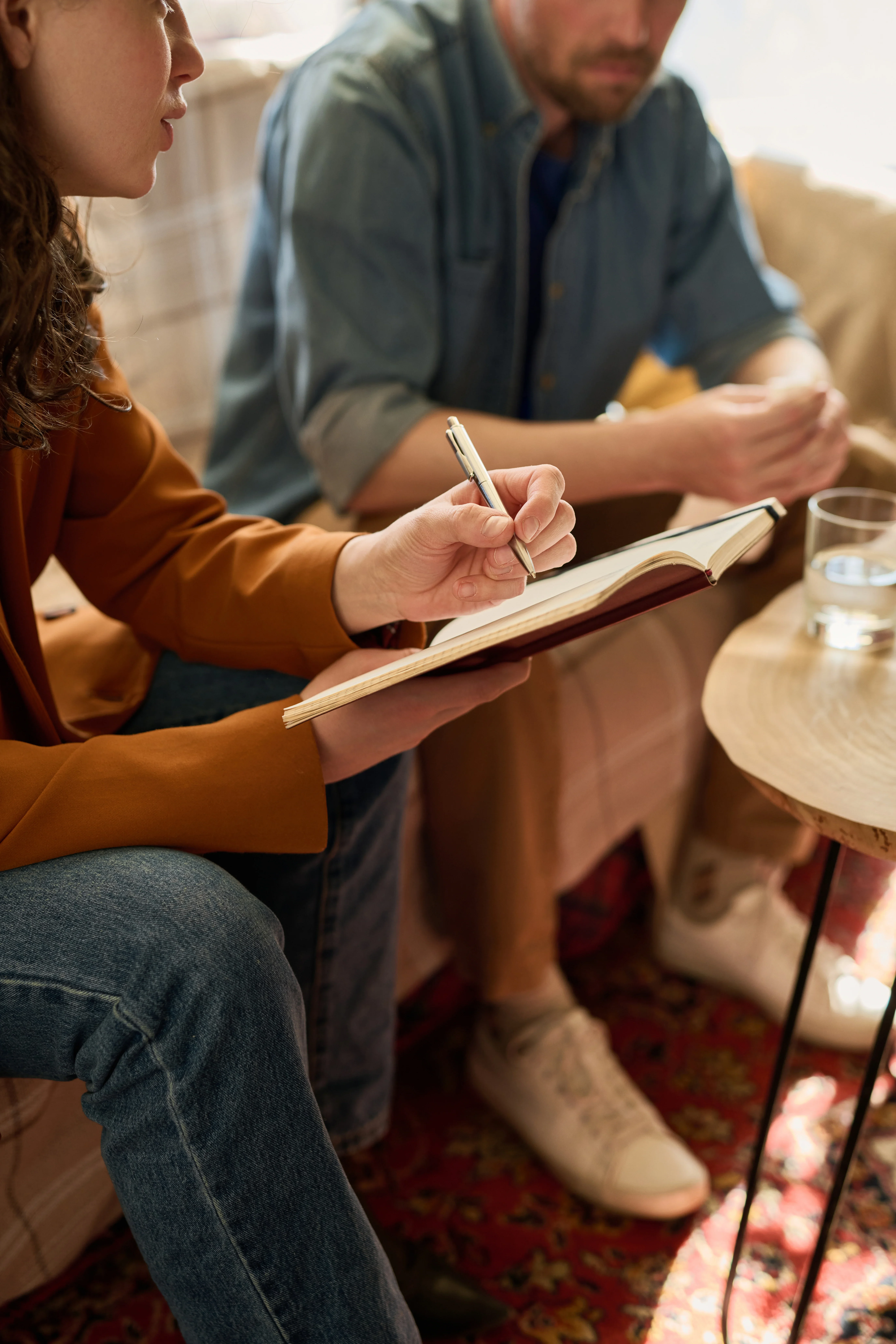 Therapist taking notes during an obsessive-compulsive disorder (OCD) therapy session with adult patient in a private counseling setting.