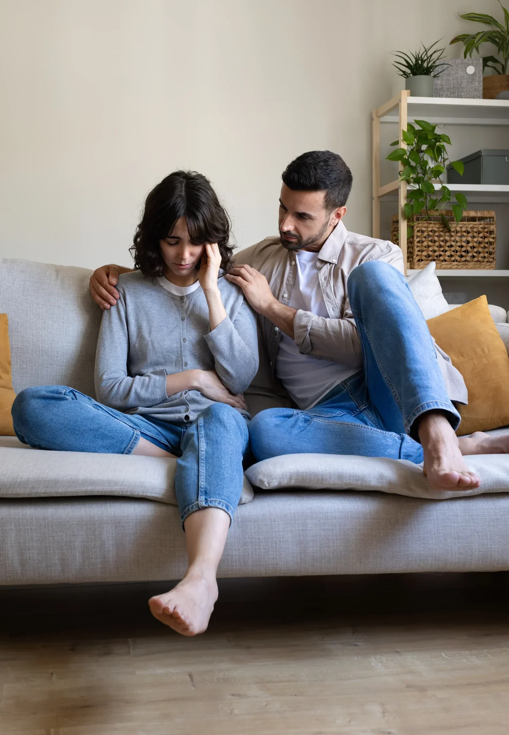 Partner comforting someone sitting on a couch at home