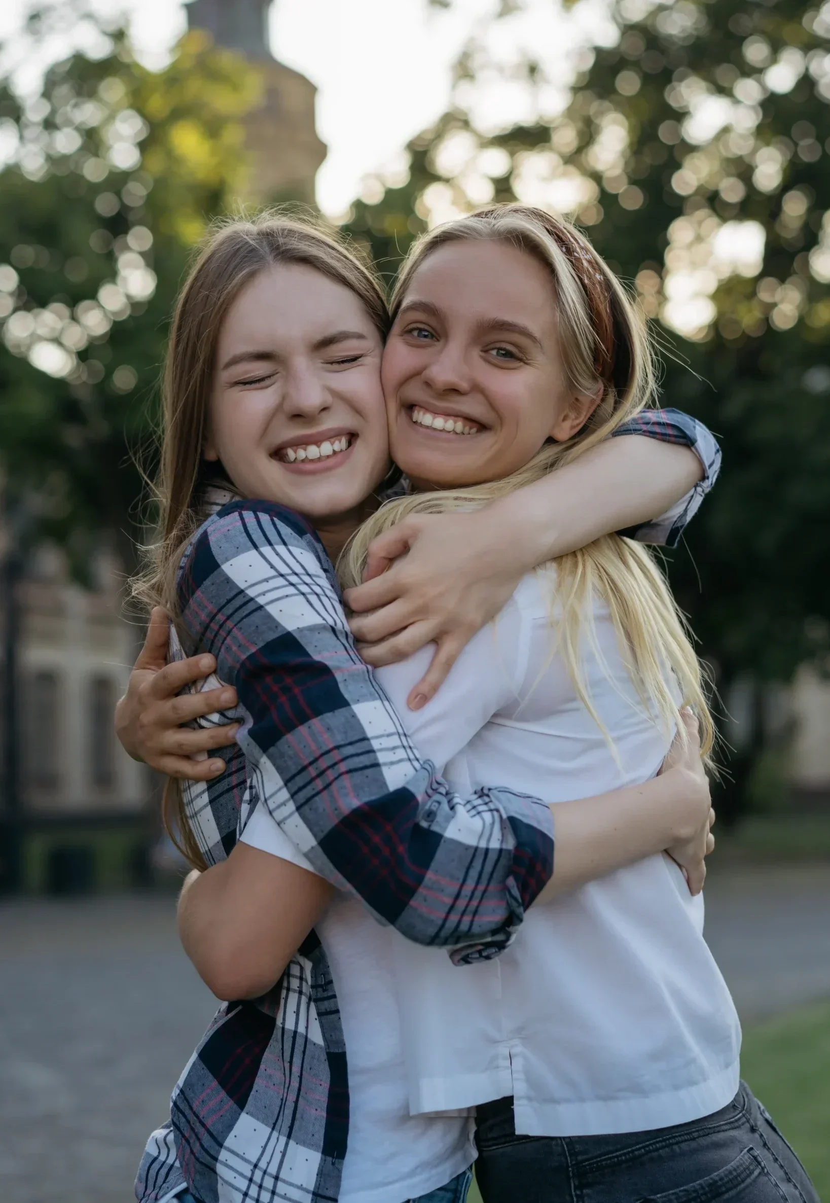 Two friends hugging outdoors and smiling