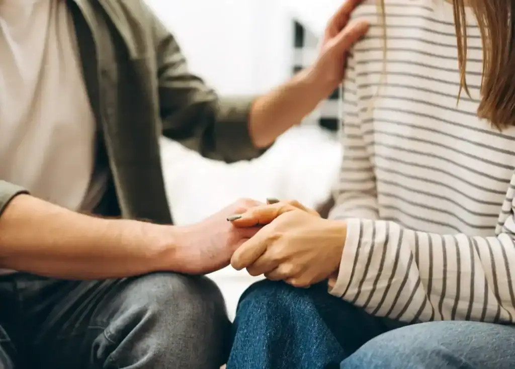 Two people holding hands in a supportive moment