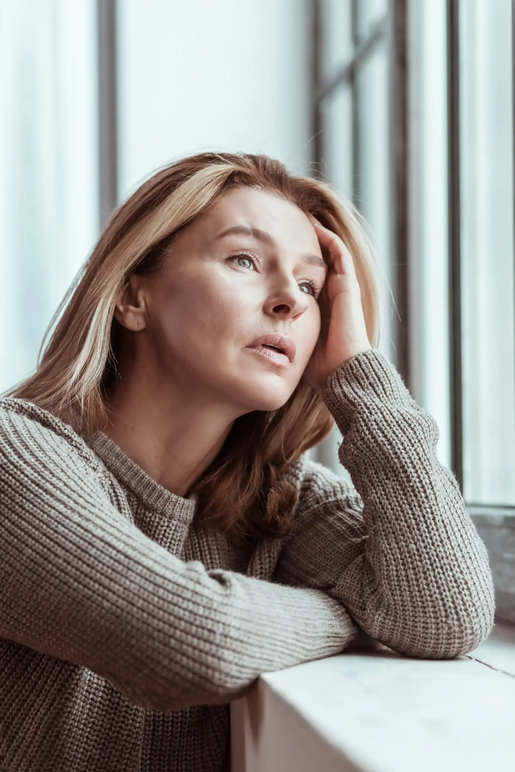 Woman looking out a window in a quiet moment of reflection