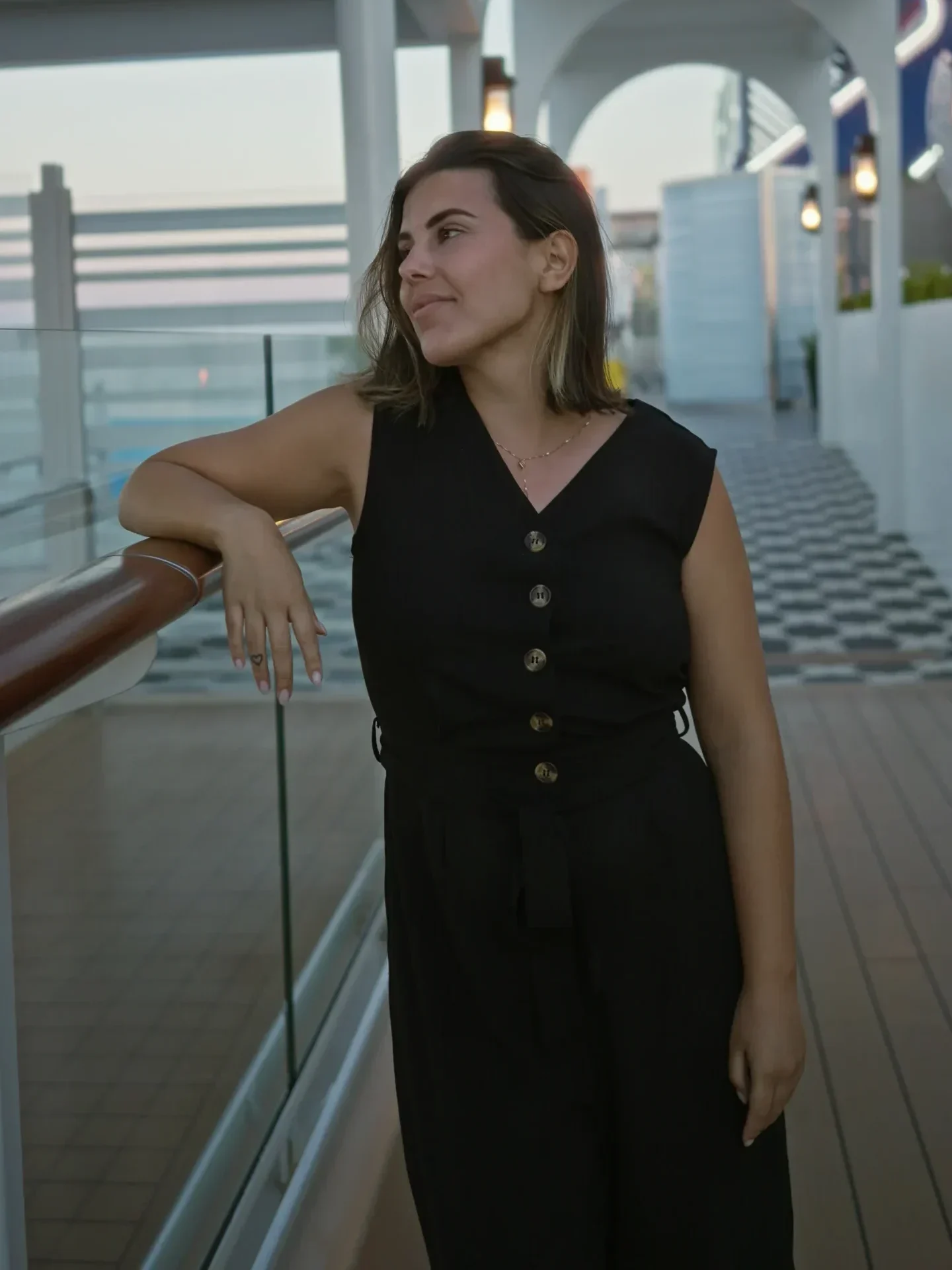 Woman leaning on a railing outdoors, looking to the side.