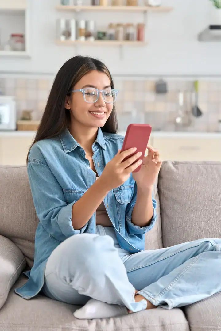 Woman using a smartphone while sitting on a couch at home