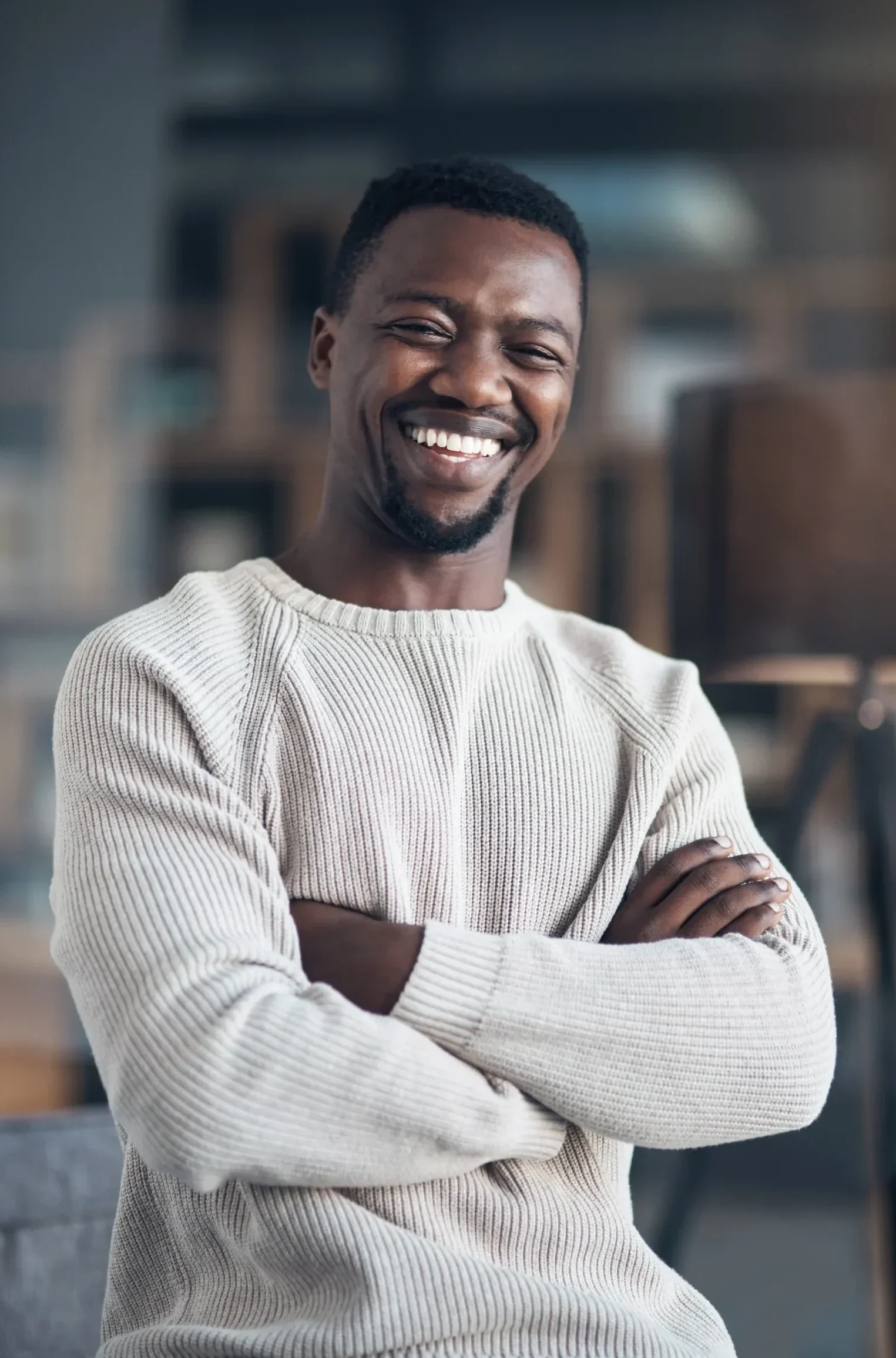 Confident man smiling in a casual sweater with a blurred office background