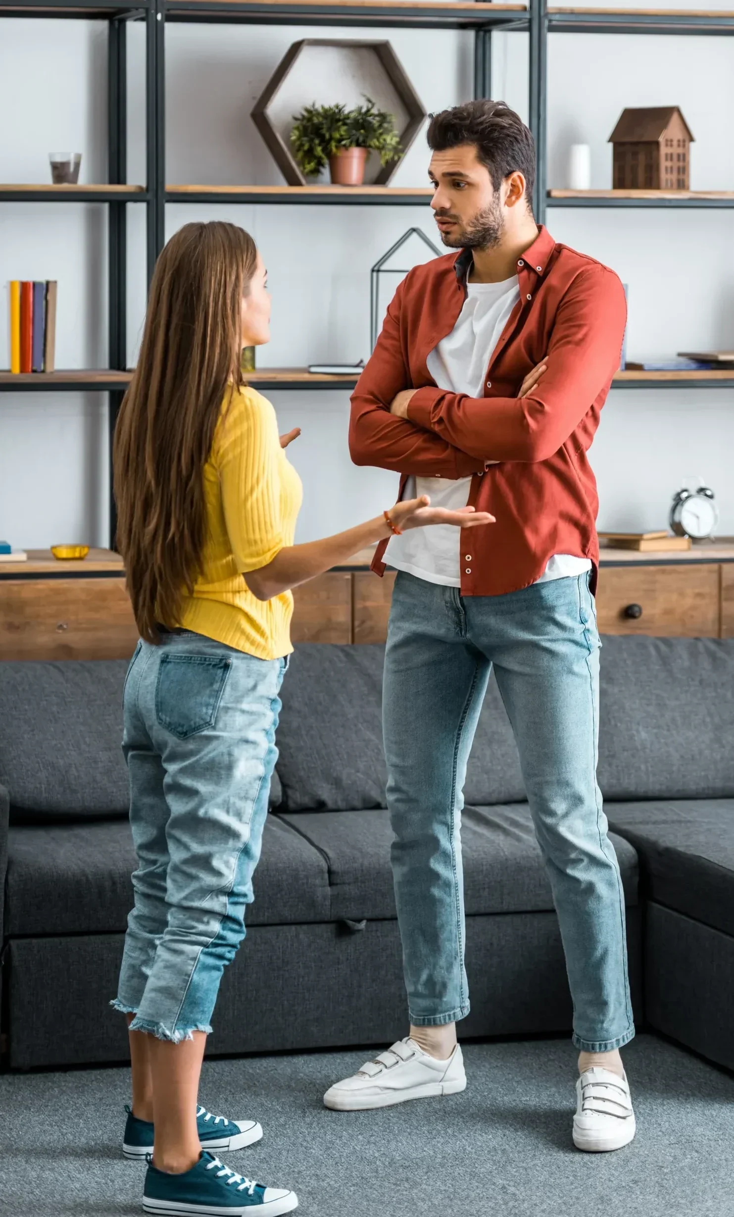 Man with arms crossed while a woman talks during a disagreement at home