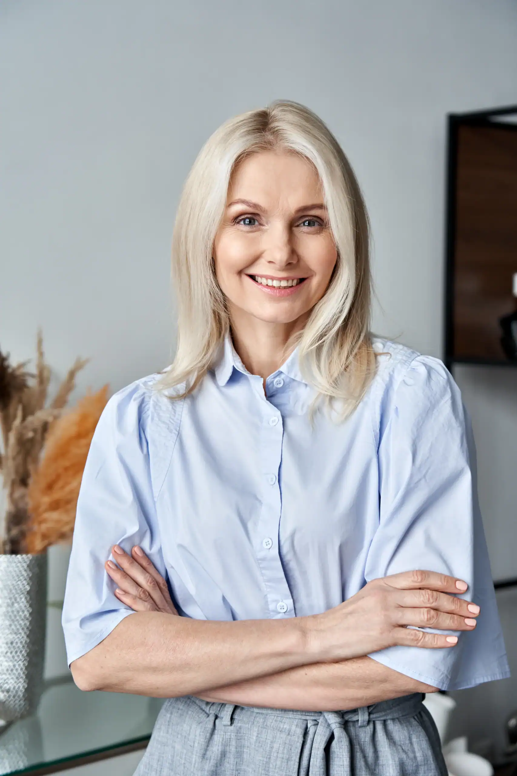 Smiling female therapist standing in an office with arms crossed