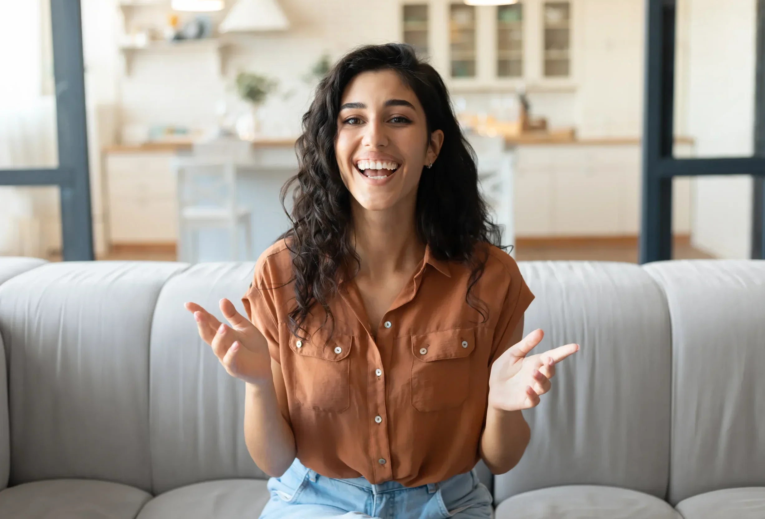 Woman laughing while seated on a couch during a friendly conversation at home