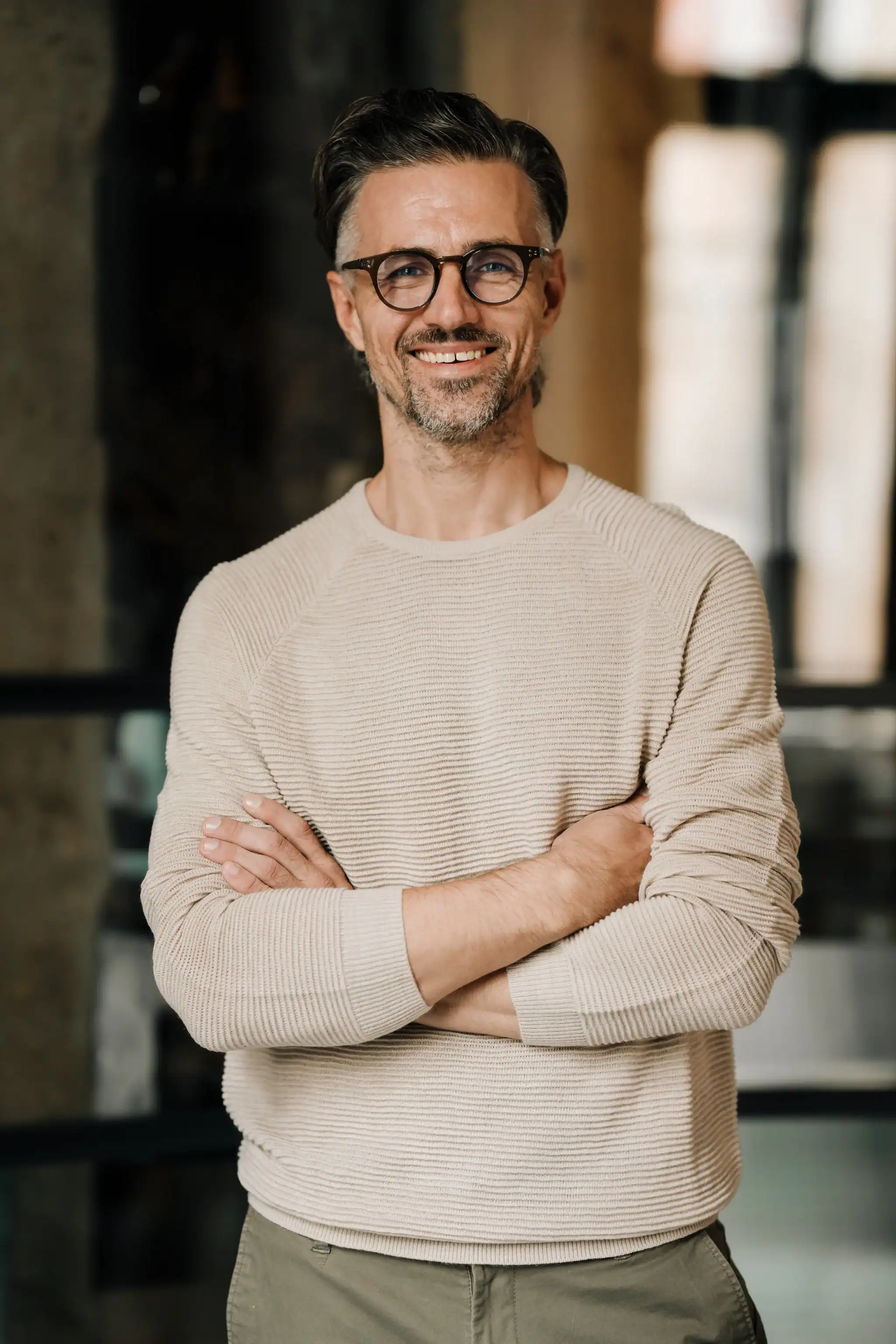 Smiling male therapist wearing glasses with arms crossed