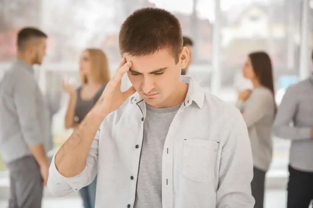 Man feeling stressed in a social setting with people in the background