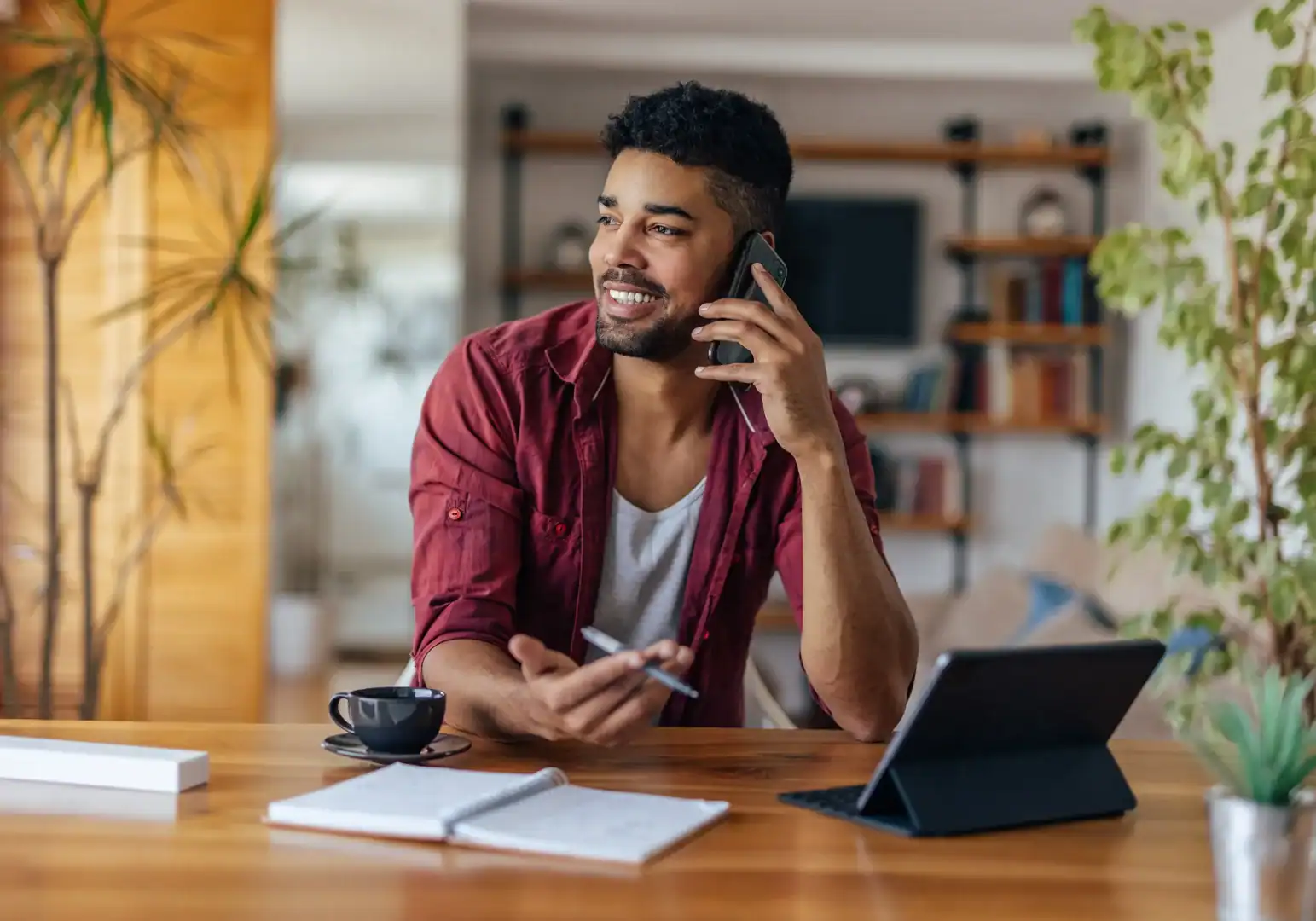 Man talking on the phone at a desk with a tablet and notebook