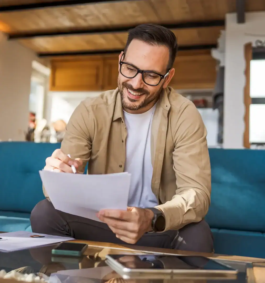 Man smiling while reviewing paperwork and writing notes