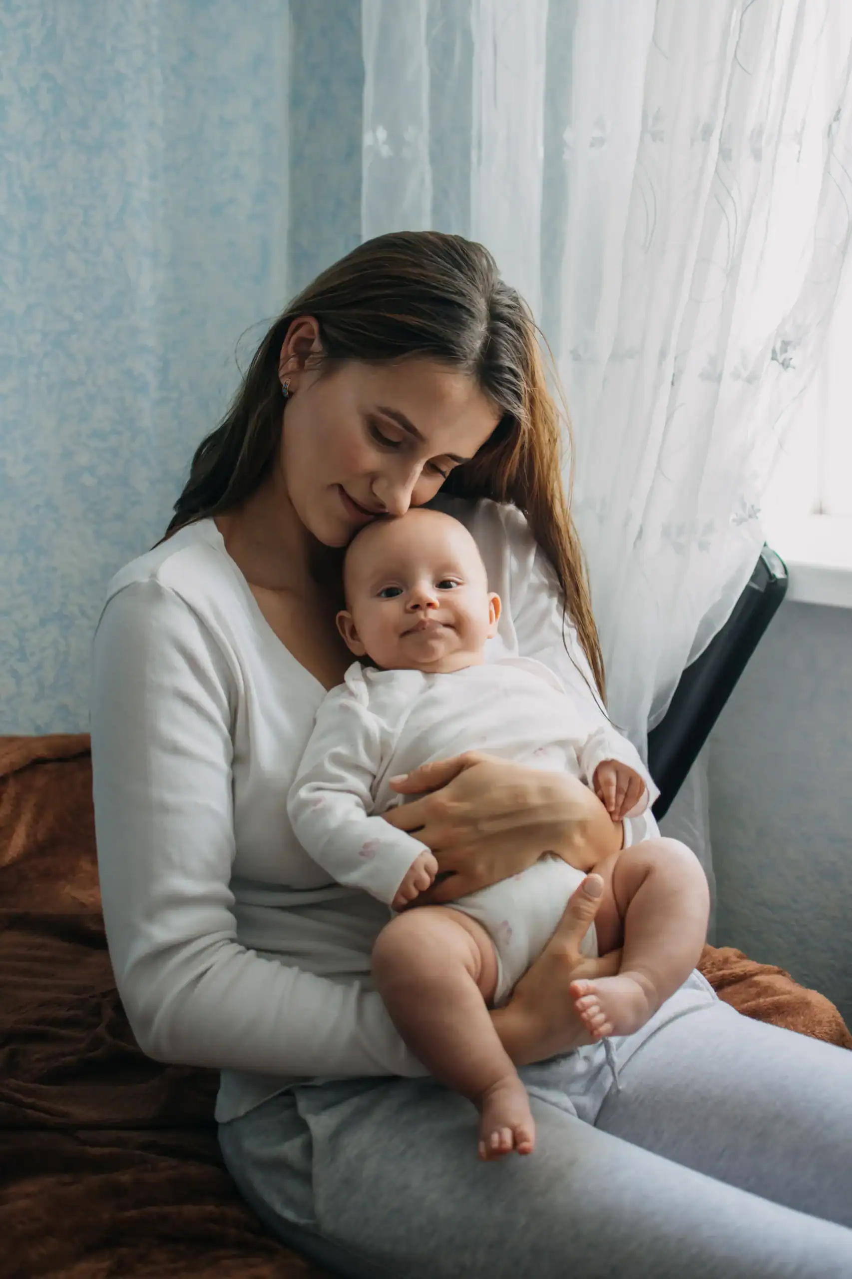 Mother holding her baby near a window