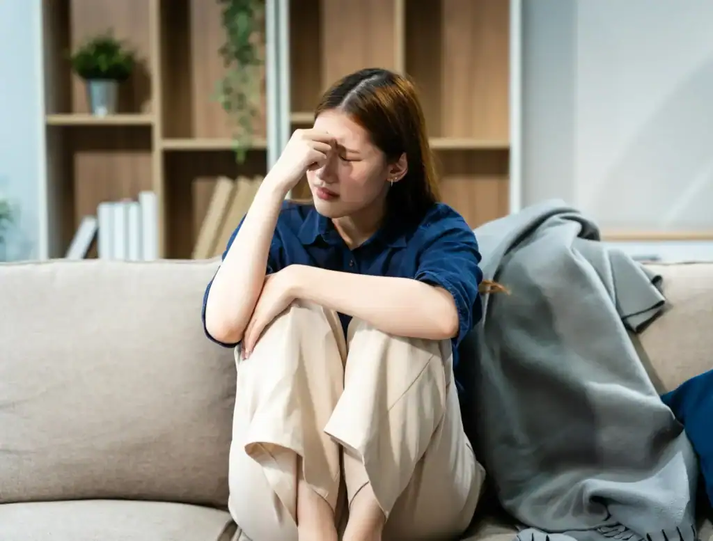 Person holding forehead while struggling with anxiety at home