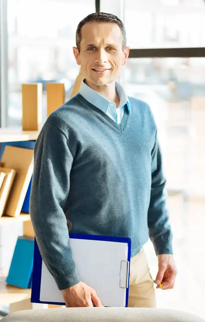 Professional man holding a folder while standing in a bright office
