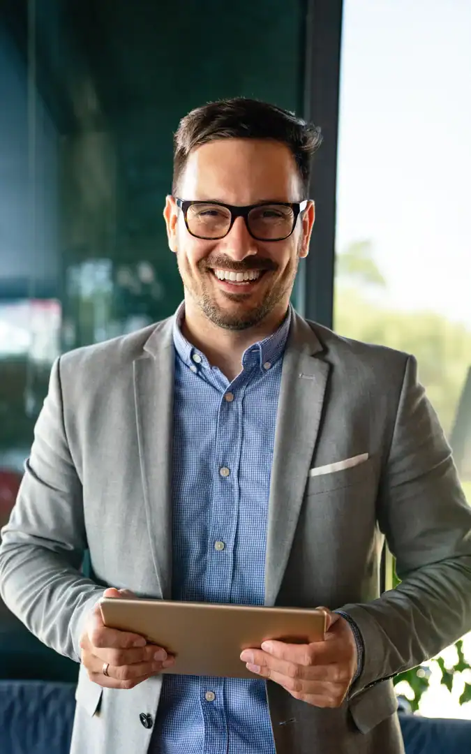 Friendly team member smiling while holding a tablet in an office setting