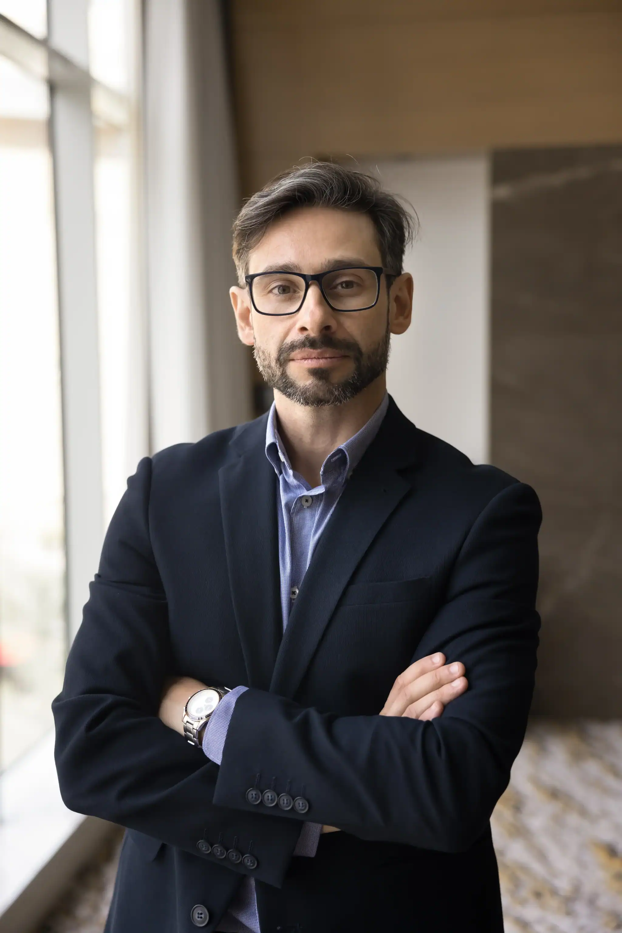Male therapist in business attire posing for a headshot near a window