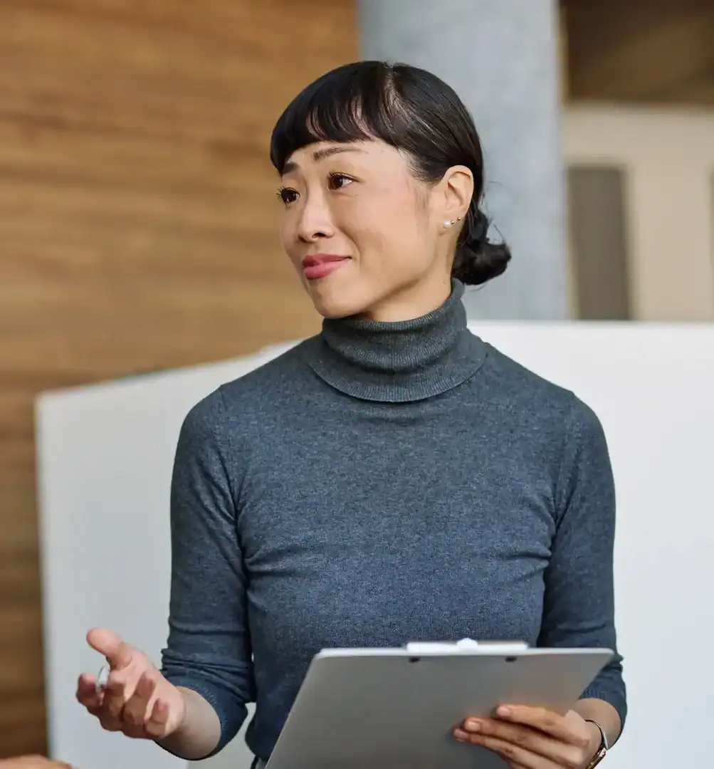 Professional woman holding a clipboard and speaking in an office