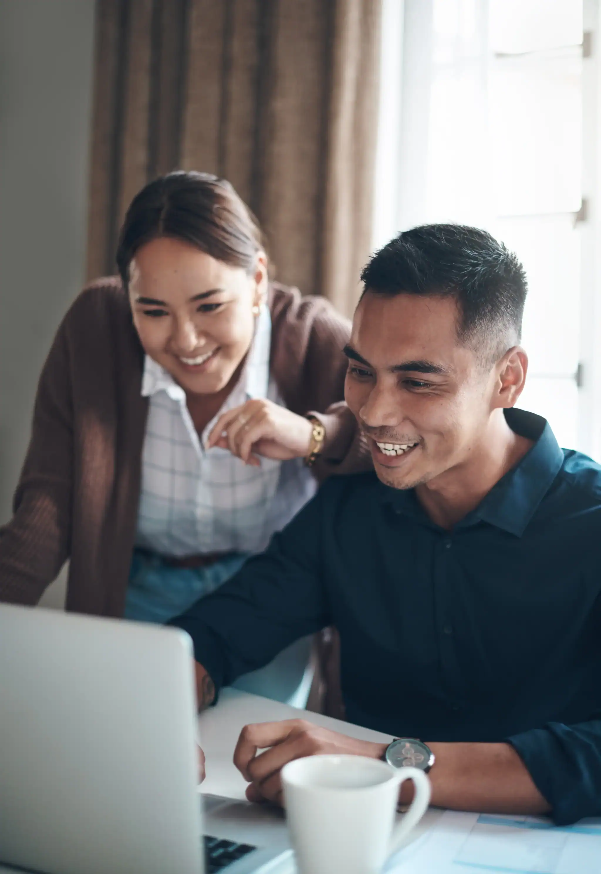 Two people smiling while looking at laptop together