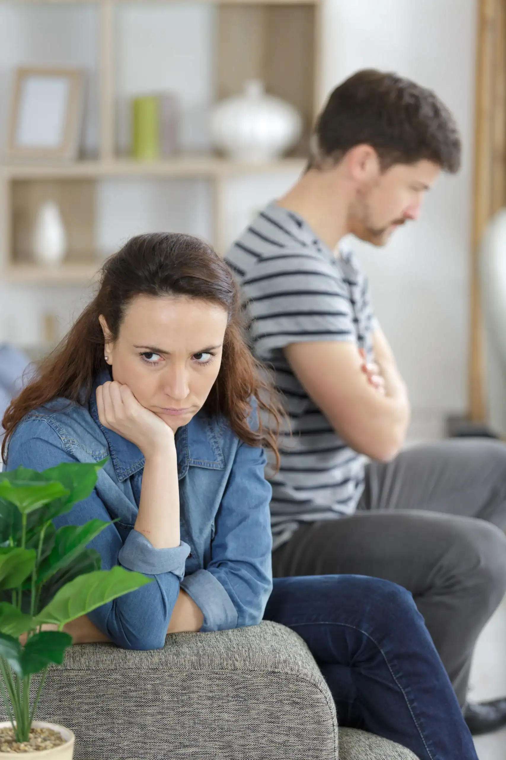 Relationship tension between a couple sitting separately in a living room