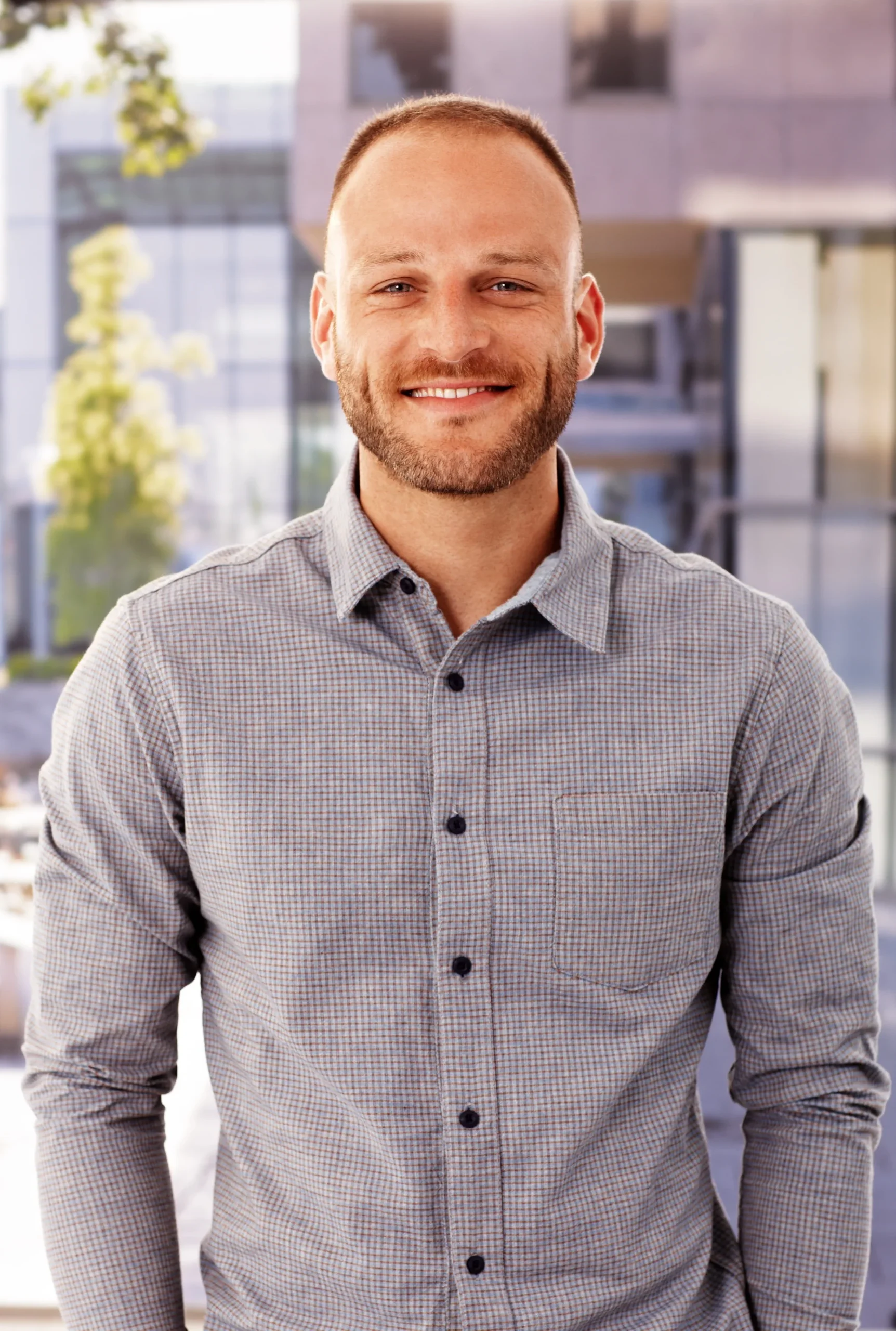 Smiling man in a patterned button-down shirt, waist-up portrait
