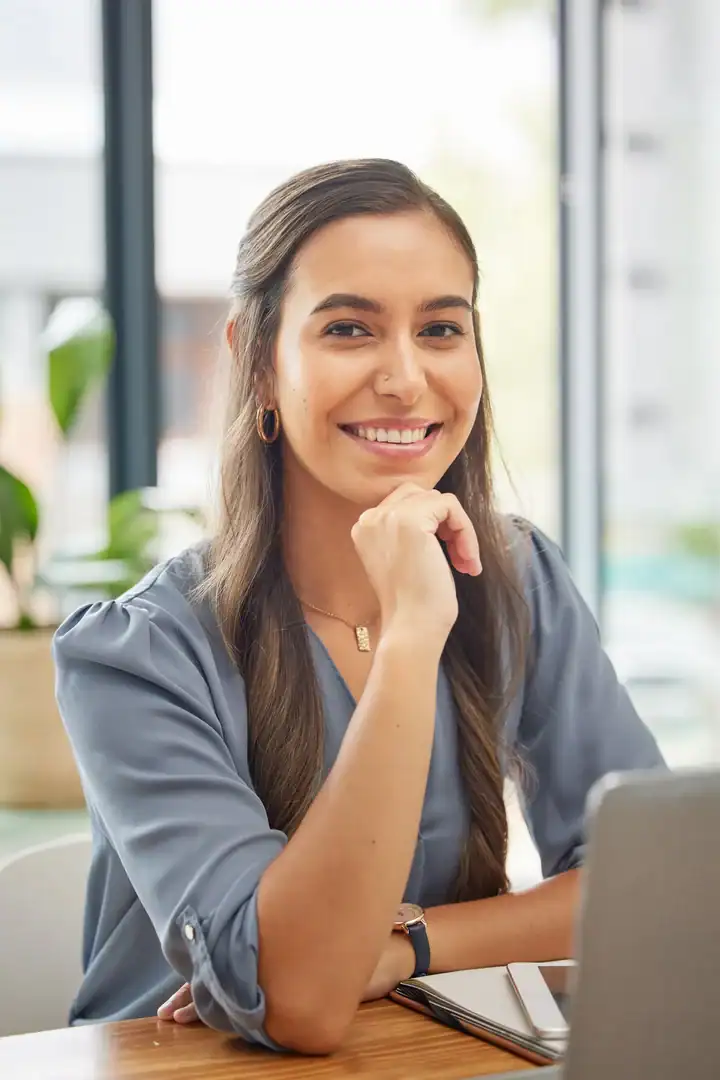 Smiling professional woman sitting at a desk with a laptop in an office