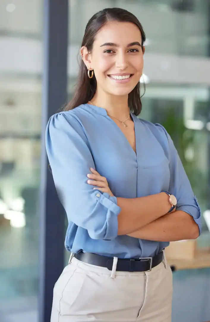Smiling professional woman standing with arms crossed in an office setting