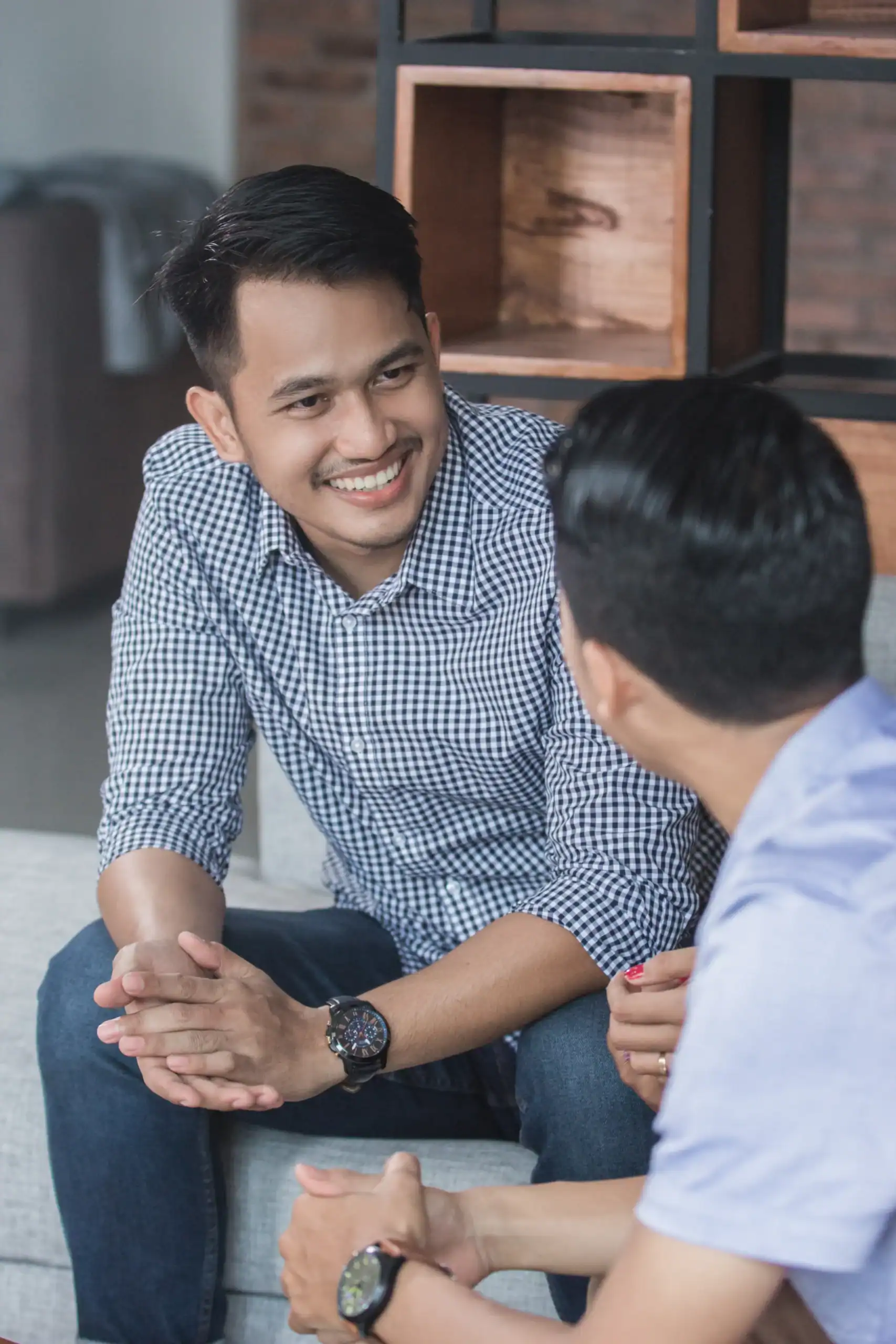 Two men seated on a couch having a supportive conversation indoors