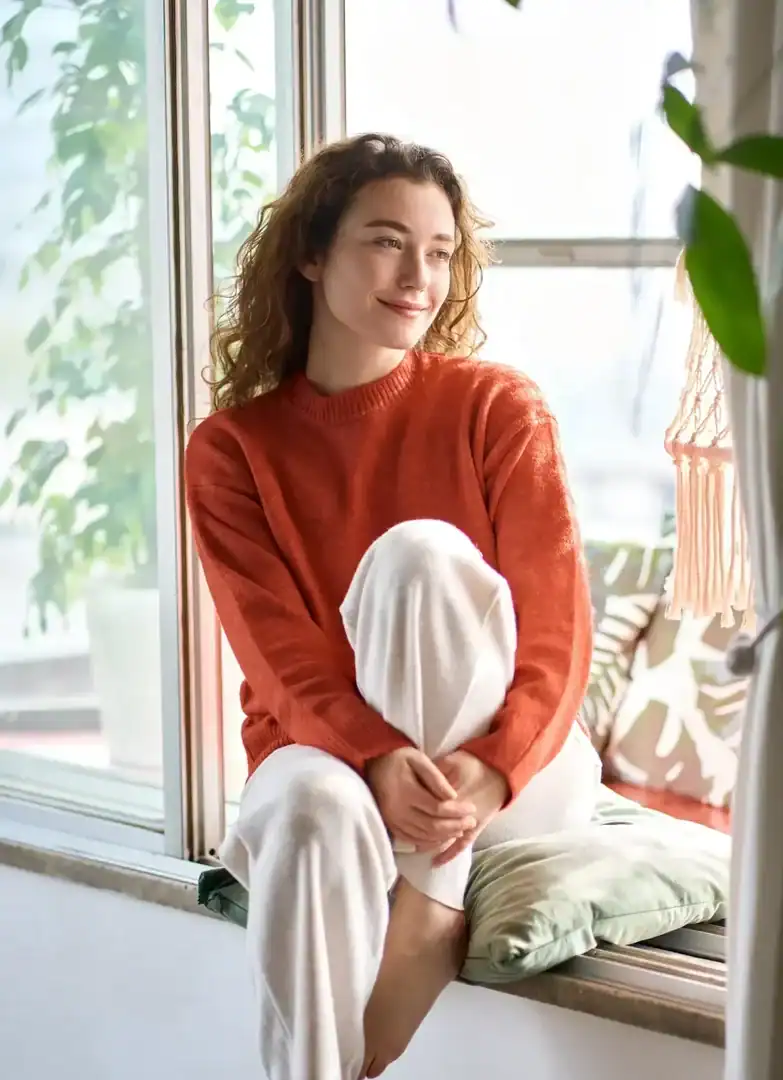 Woman sitting by a window in a calm moment of reflection at home